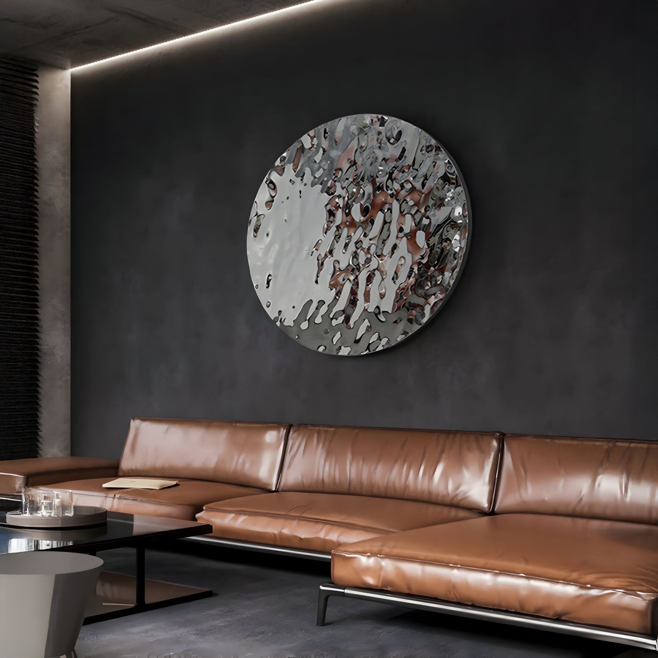 A modern living room with a brown leather sectional sofa, round coffee table, and the Lumineris Silver Ripple Sphere Metal 3D Wall Art by Giant Sculptures mounted on a dark gray textured wall.