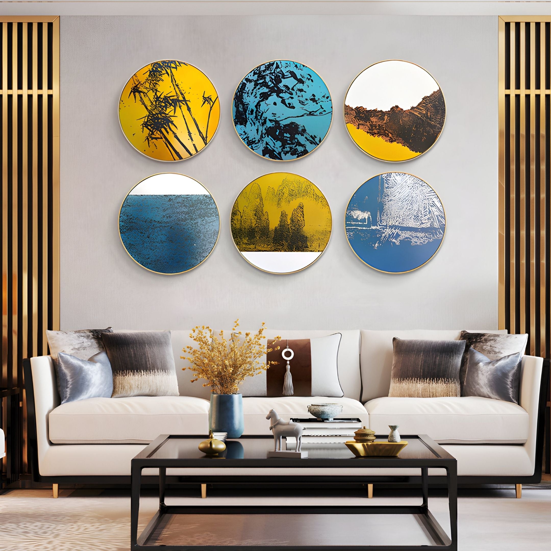 A modern living room features a white sofa, black coffee table, gold accents, and Giant Sculptures’ Auralune Blue Horizon Abstract Round 3D Wall Art—six blue, yellow, white, and brown 3D pieces—mounted on a gray wall above the sofa.