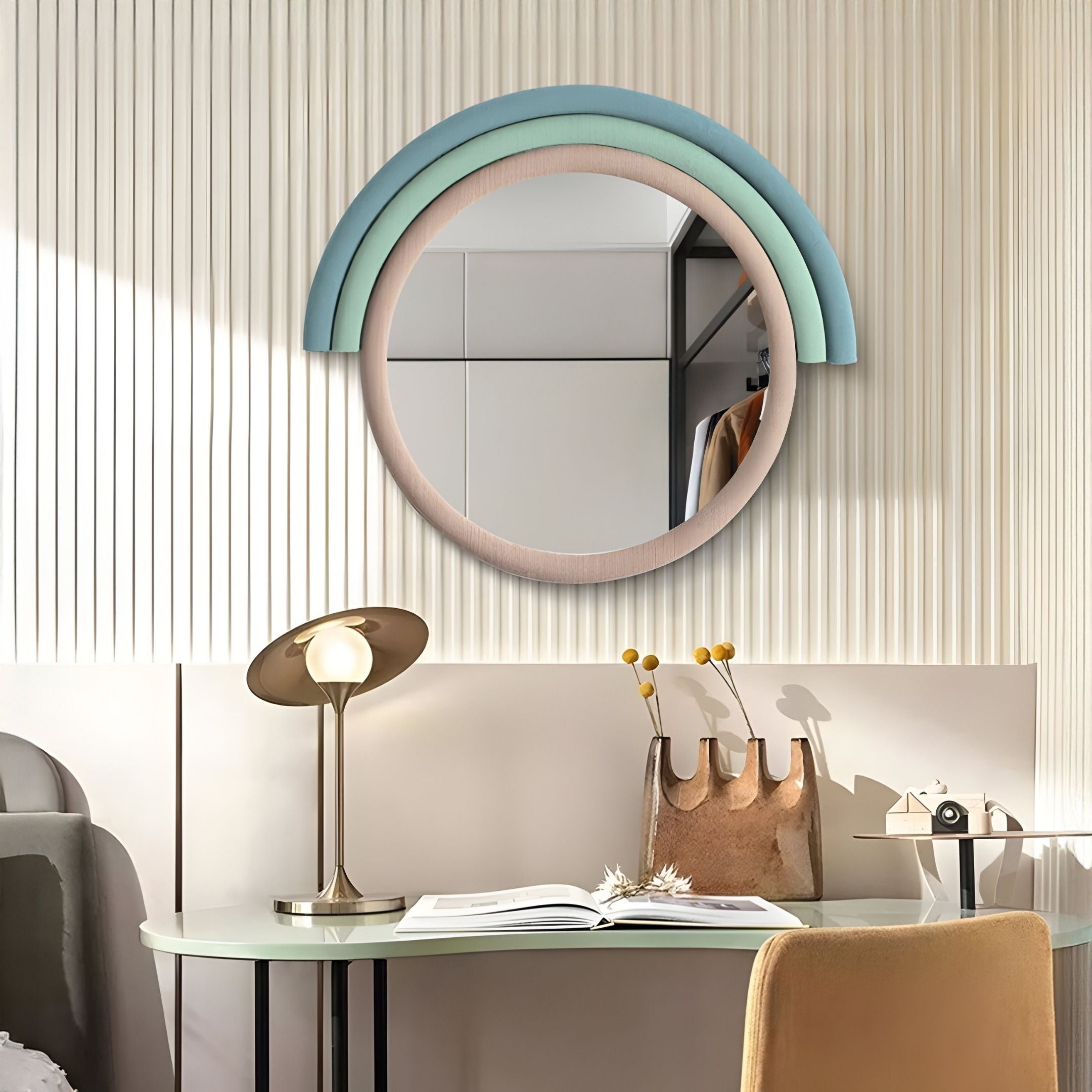 A modern desk with a brass lamp, open book, and beige bag sits against a ribbed white wall. Above is the Arcaluna Sky & Mint Layered Round Mirror 3D Wall Art by Giant Sculptures, featuring pastel accents for Nordic flair.