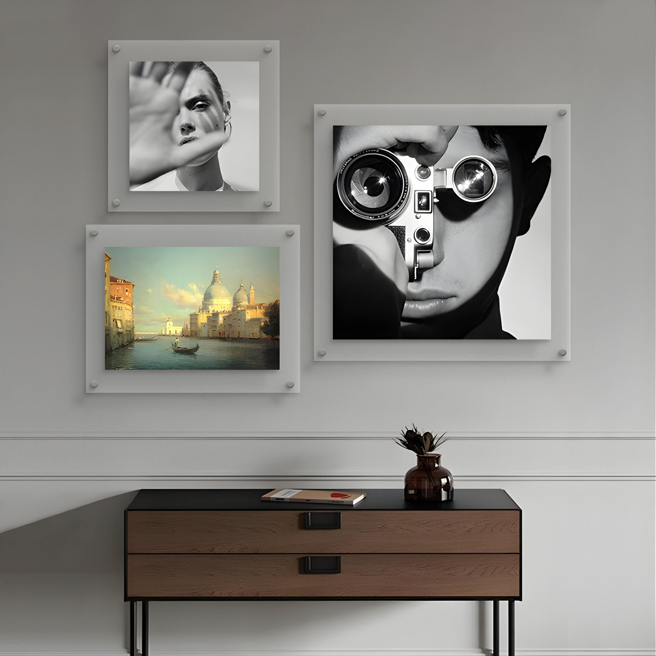 A modern wall features the Giant Sculptures CineLuxe Venice Glow Landscape 3-Panel Acrylic Wall Art above a wooden console table with a vase and books—an elegant touch for contemporary interiors.