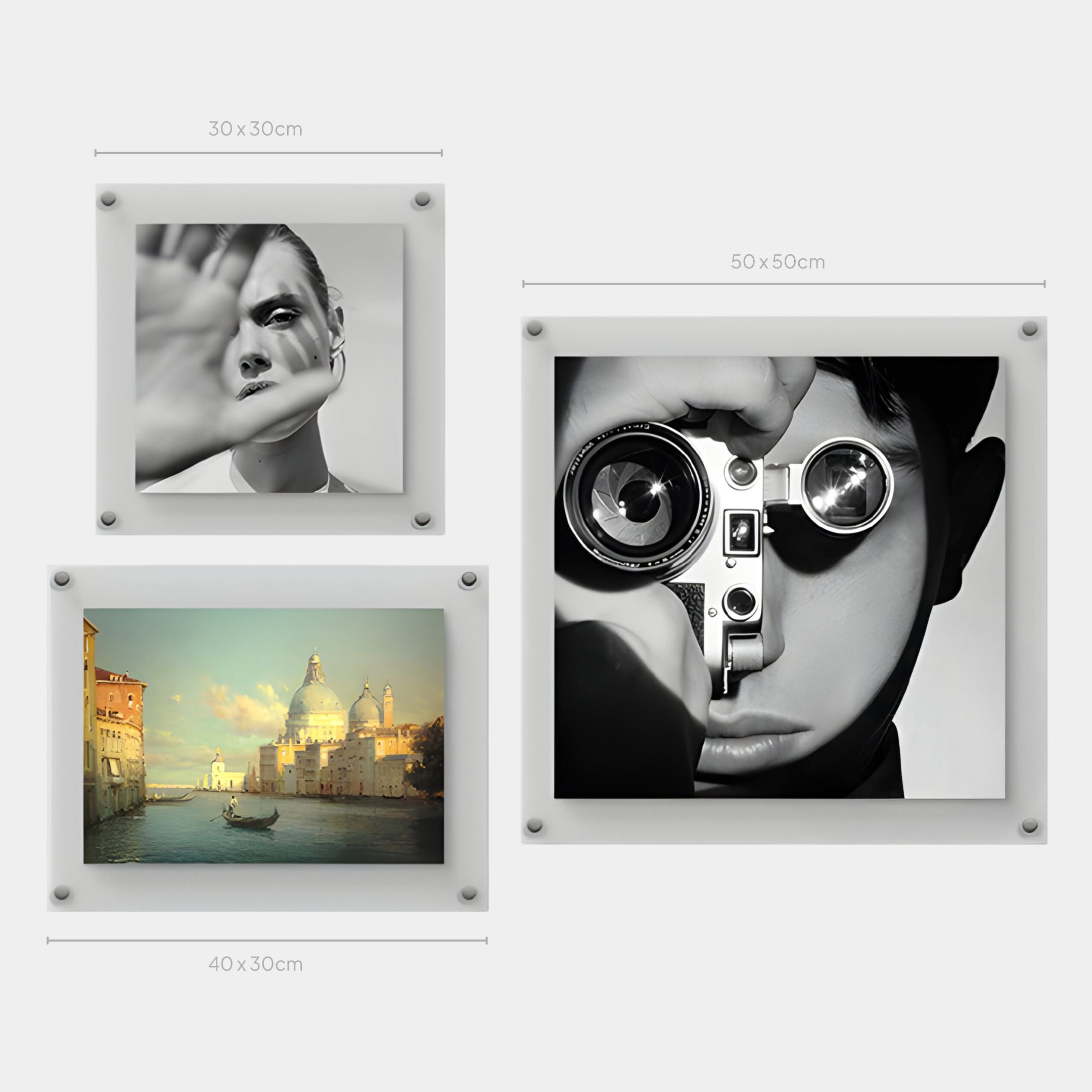 Three framed pictures on a wall: two black-and-white portraits (one with a raised hand, one holding a camera), and the Giant Sculptures CineLuxe Venice Glow Landscape 3-Panel Acrylic Wall Art—ideal for modern interiors.