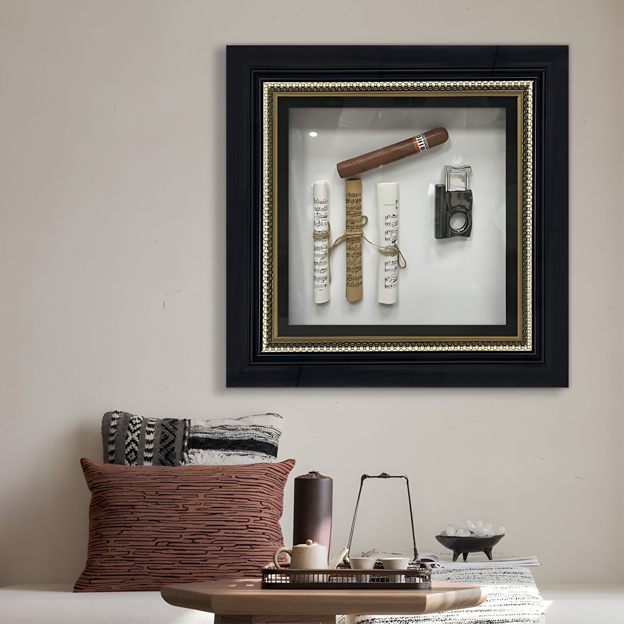 A modern living room features a low table, cushions, and CurioVault Cigar & Sheet Music Framed Wall Art by Giant Sculptures on the wall—a display case with a cigar, sheet music rolls tied with string, and a vintage camera.