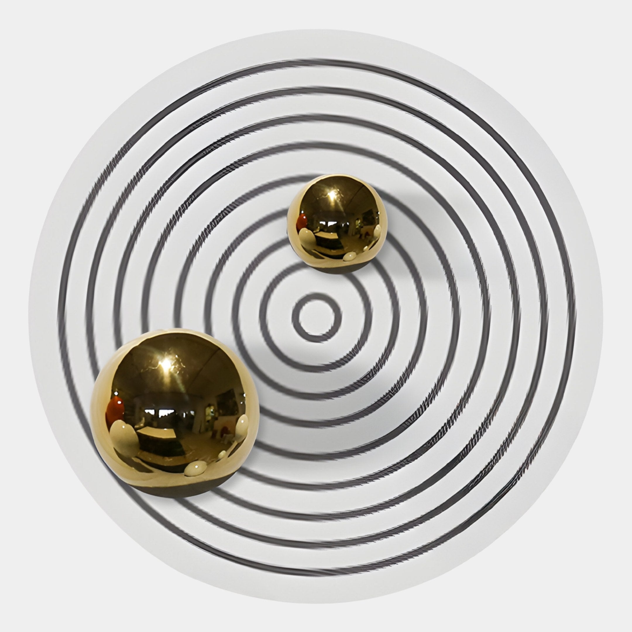The Orbiora III Gold Duo Concentric Sphere 3D Wall Art by Giant Sculptures features two reflective gold spheres of varying sizes on a white surface with black concentric circles, creating a striking modern optical illusion.