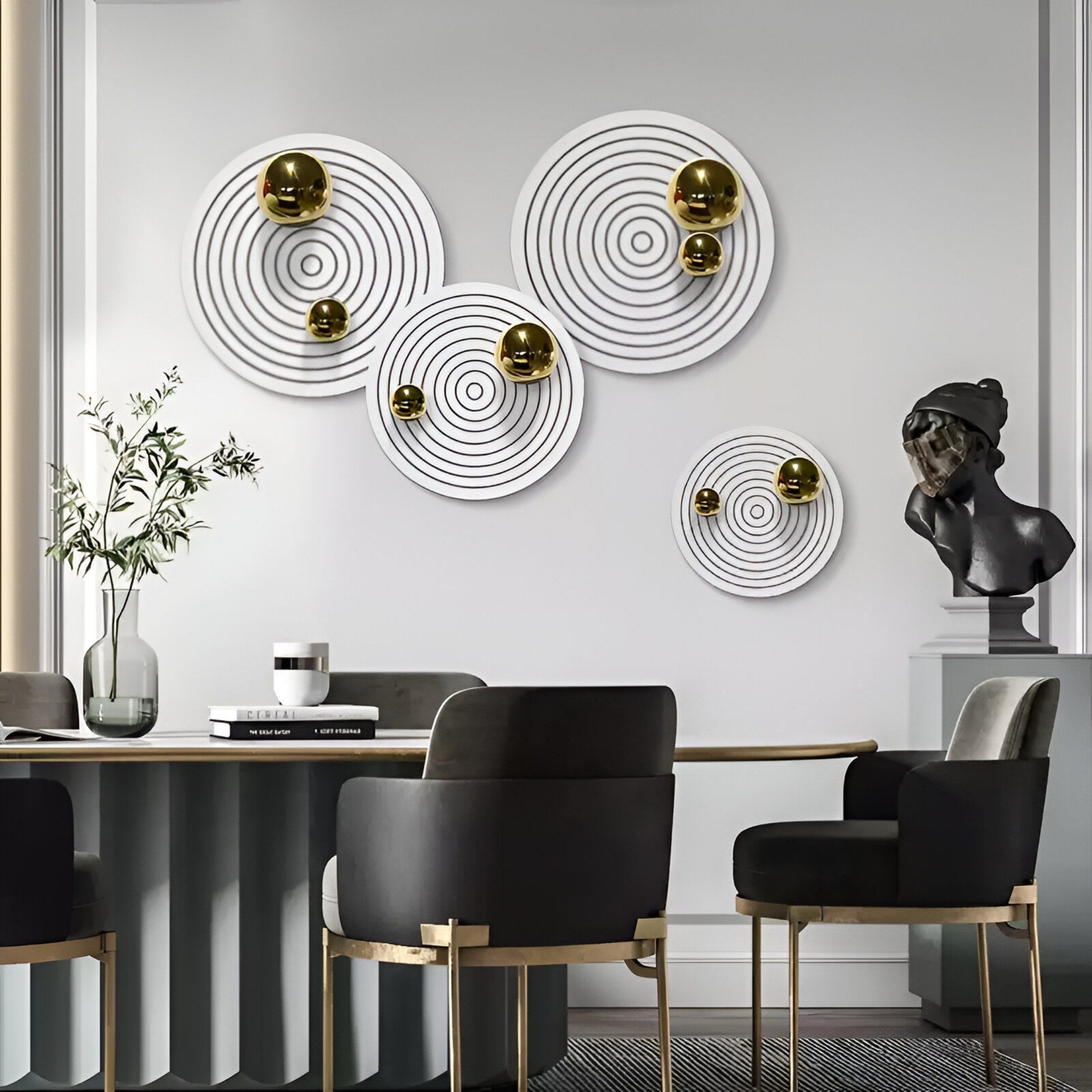 A modern dining room with a round table, gray and gold chairs, a plant centerpiece, a black sculpted bust on a pedestal, and Giant Sculptures’ Orbiora Gold Orb 4-Panel Concentric Sphere 3D Wall Art as an eye-catching feature.