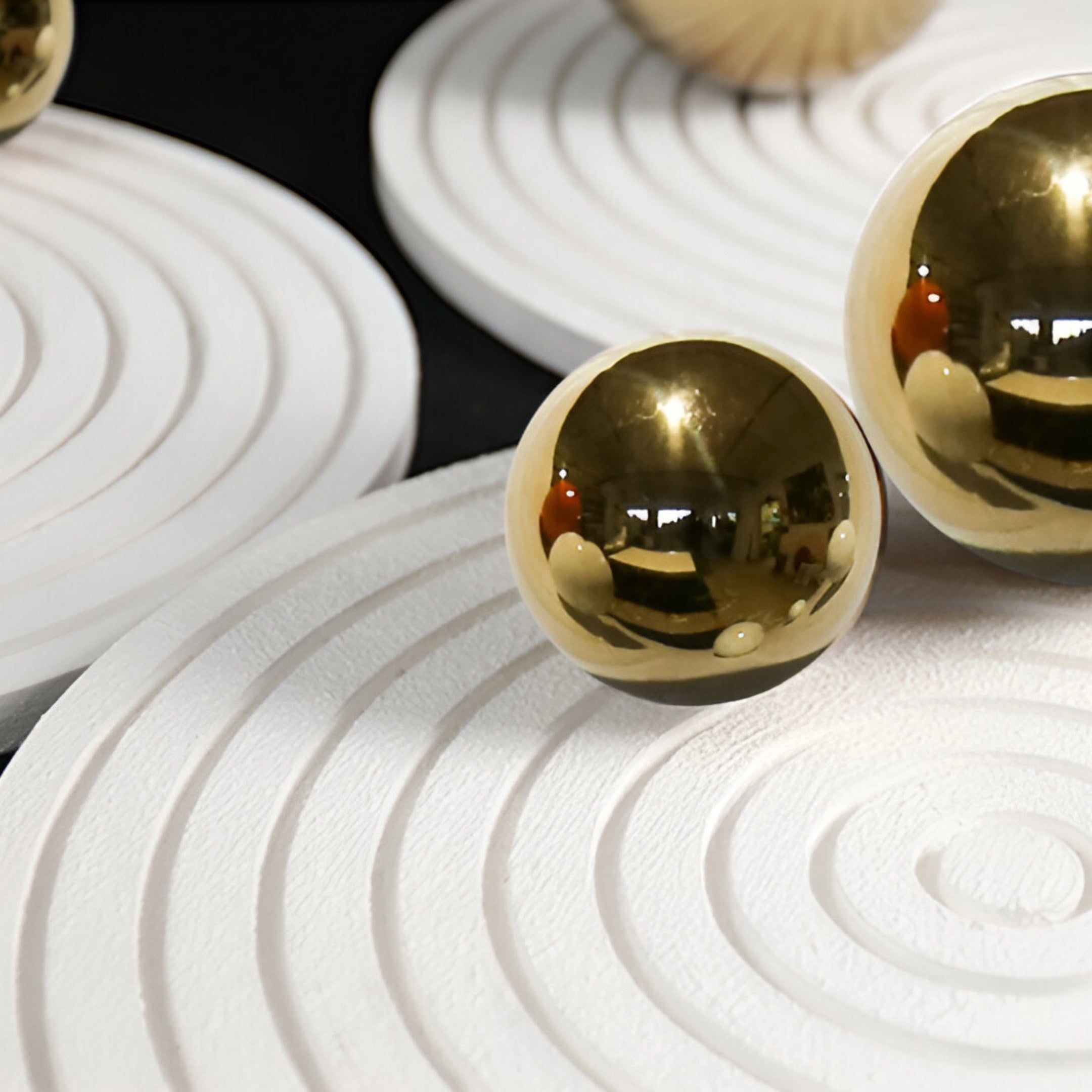 Two gleaming gold spheres, as seen in Giant Sculptures' Orbiora Gold Orb 5-Panel Concentric Sphere 3D Wall Art, sit on textured white concentric platforms against a dark backdrop, their surfaces reflecting the light.