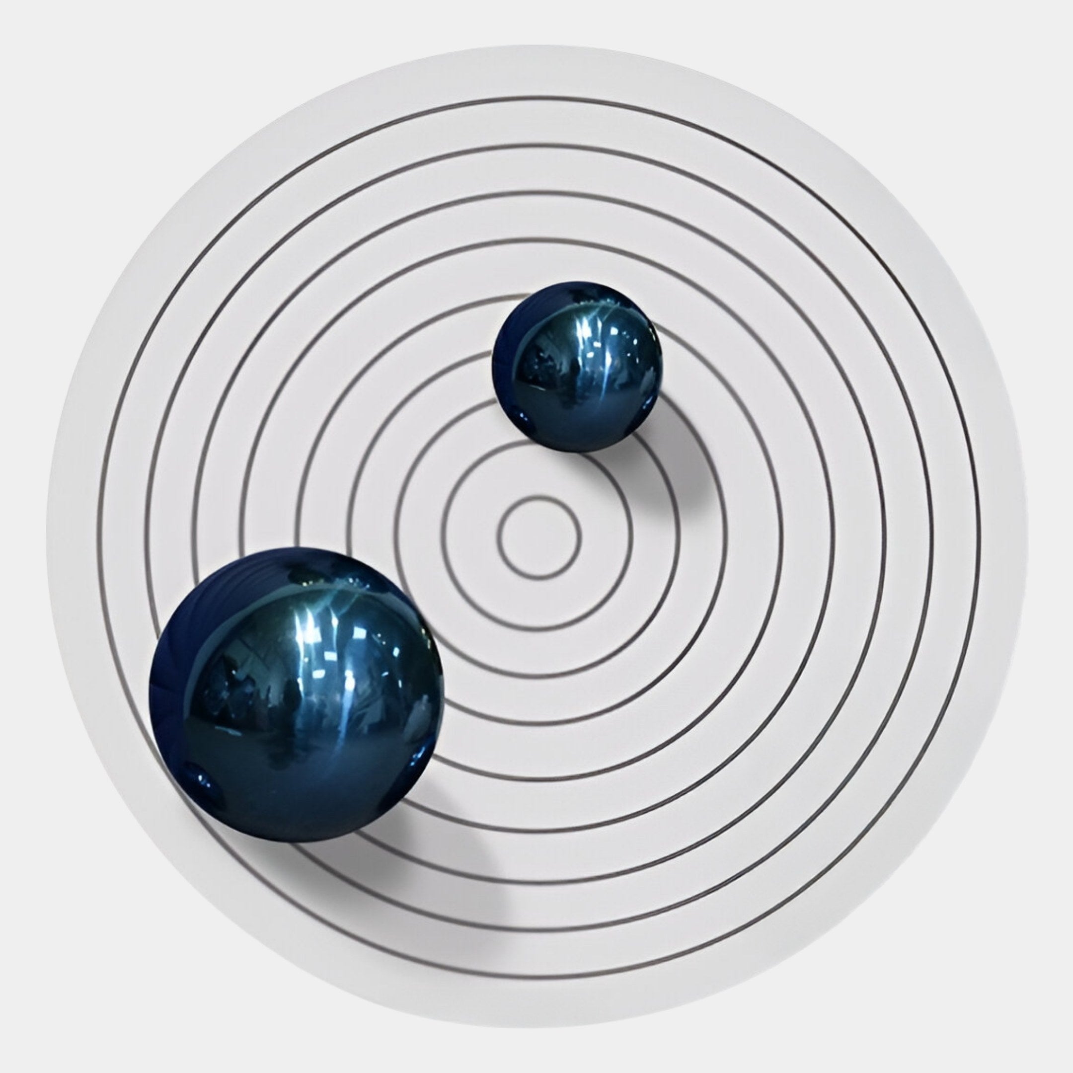 Orbiora III Blue Duo Concentric Sphere 3D Wall Art by Giant Sculptures features two blue metallic spheres on black concentric circles over a white surface, creating an abstract, minimalist look—ideal for modern wall decor.