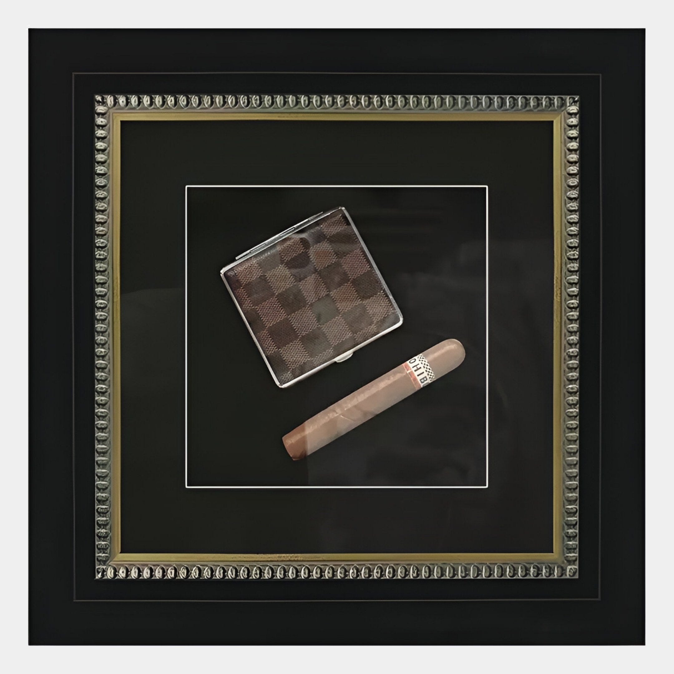The Havantra Cigar & Checked Case Framed Wall Art by Giant Sculptures showcases a checkered wallet and cigar on a black matte background, beautifully enclosed in an ornate, silver-trimmed frame—perfect masculine decor.