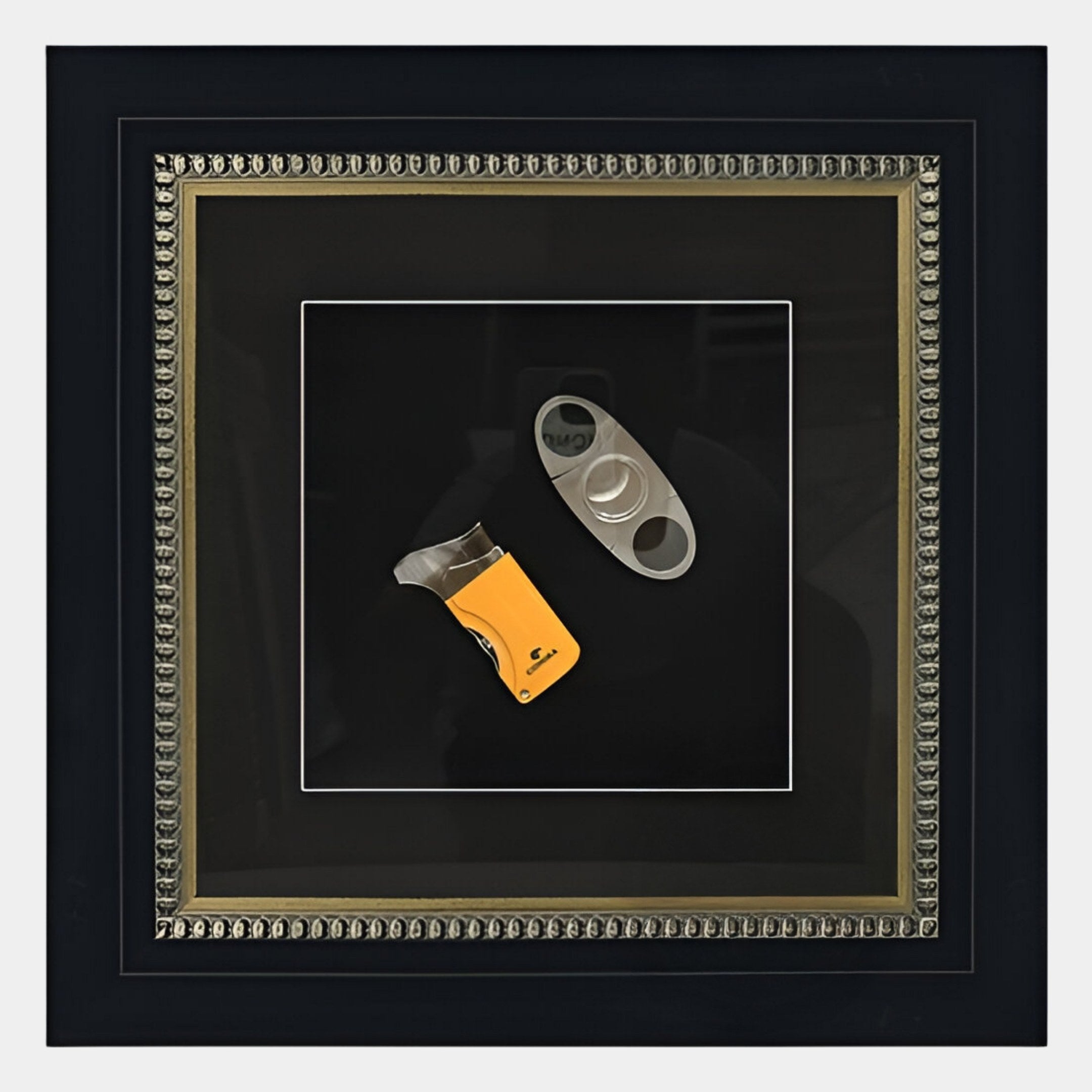 The Havantra Cutter & Torch Cigar Accessory Framed Wall Art by Giant Sculptures showcases two distinct cigar cutters set against a black background with an ornate border, perfect for cigar enthusiasts’ décor.