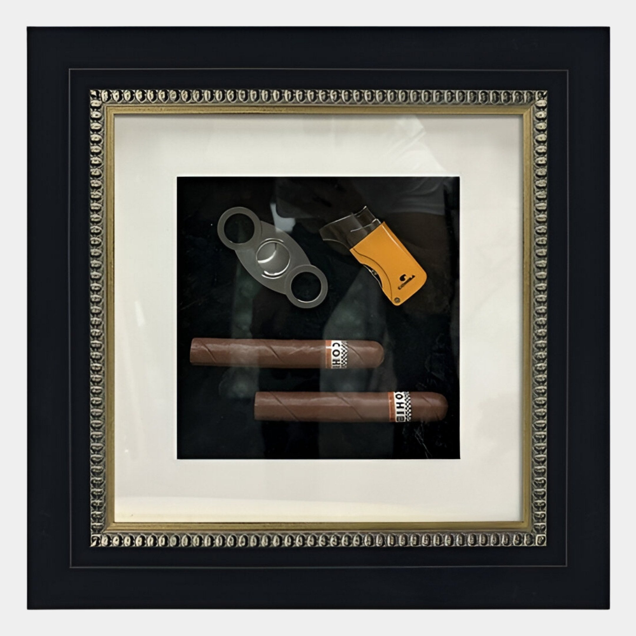 The Havantra Double Cigar & Cutter Framed Wall Art by Giant Sculptures features two cigars, a cutter, and a yellow lighter set against a black background with a white mat in an ornate black frame.