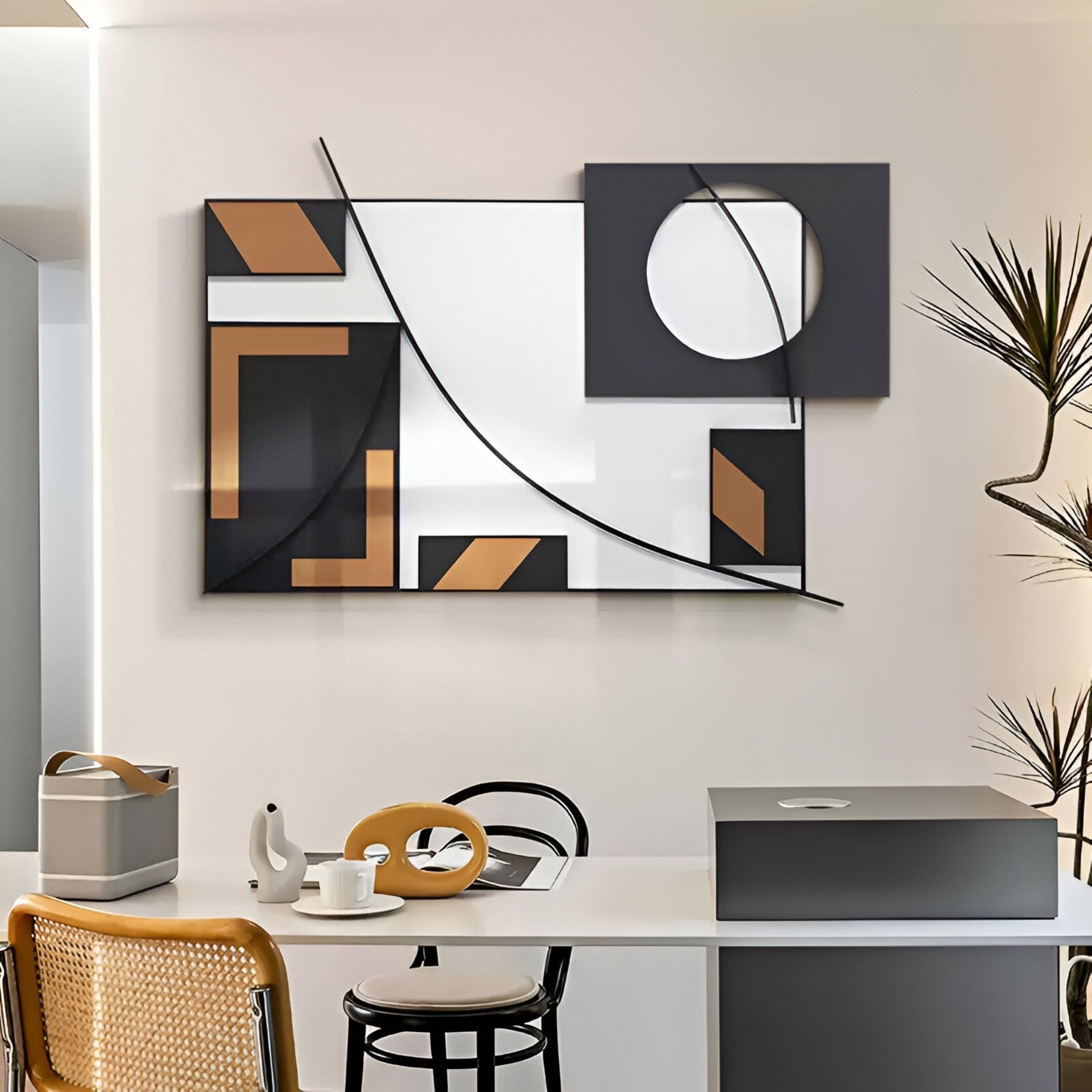 A modern home office featuring Struktura Bronze & Black Geometric Curve 3D Wall Art by Giant Sculptures, a white desk with a teapot and cup, mesh chair, and a potted plant to the right.