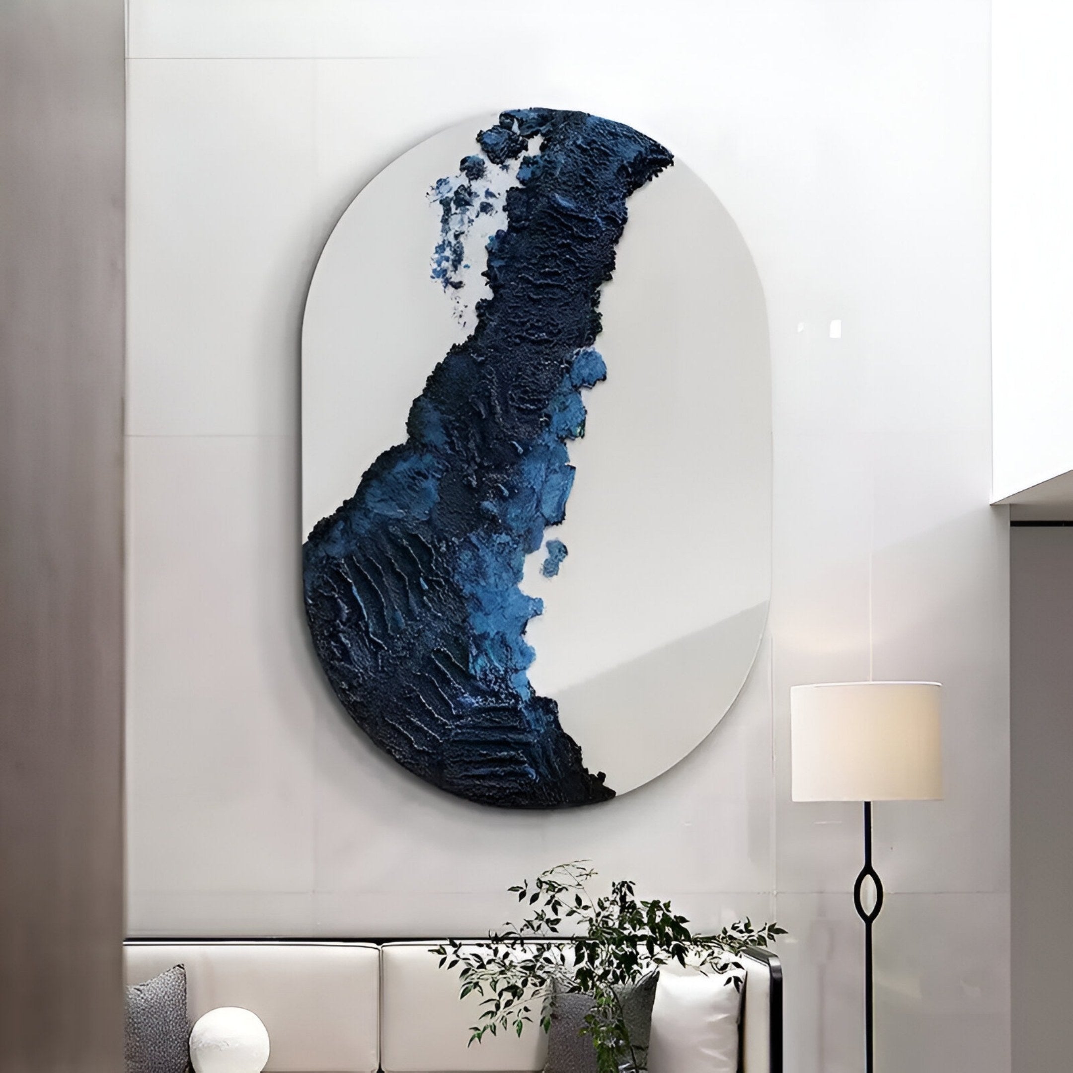 The Orrica Midnight Blue Textured Relief 3D Wall Art by Giant Sculptures hangs above a modern white sofa with a cushion, accompanied by a tall floor lamp and small plant for a tranquil minimalist living room.