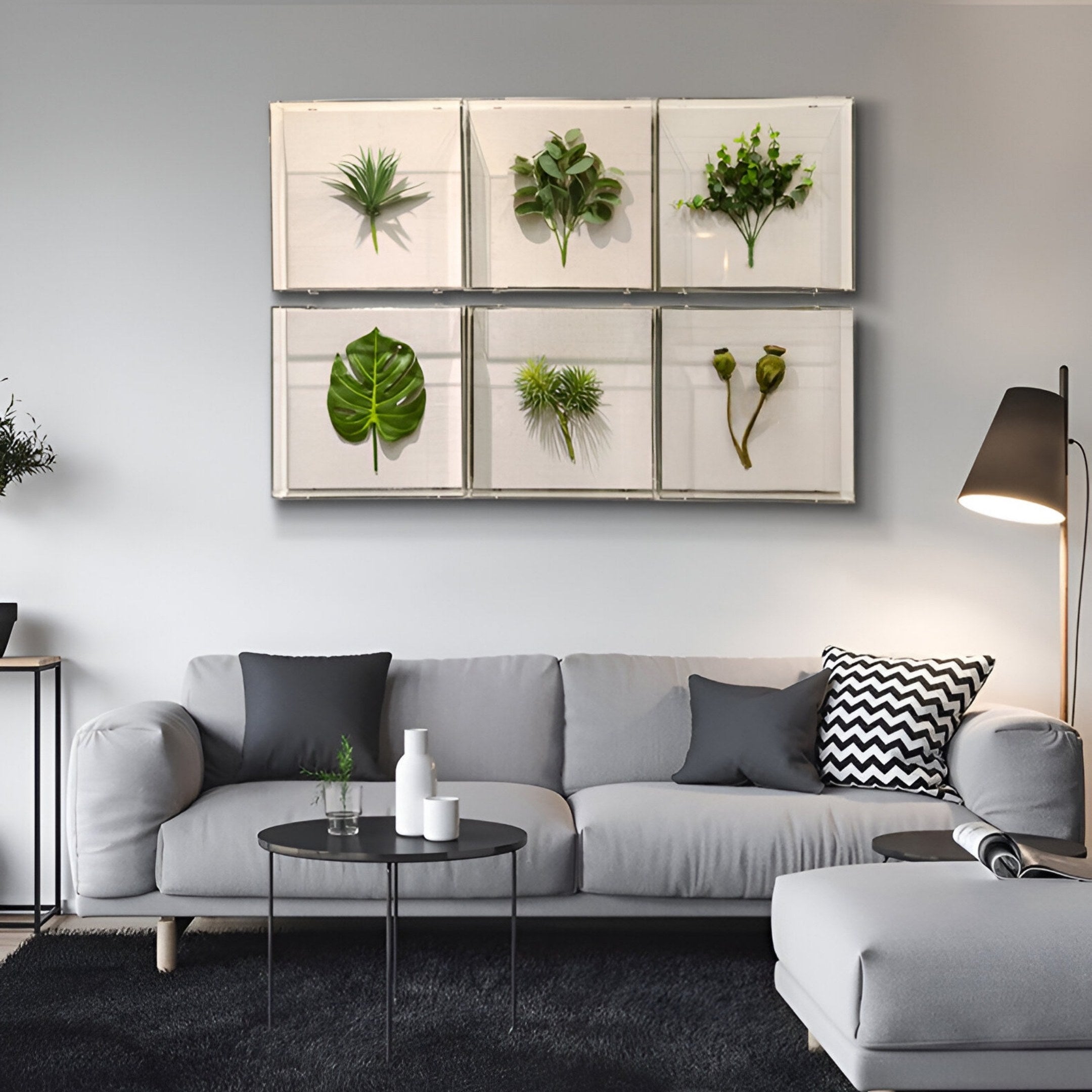 A modern living room features a light gray sofa with black and white cushions, black tables, and the Florvara Botanical Leaves 6-Panel Acrylic 3D Wall Art by Giant Sculptures. A floor lamp beside the sofa completes the Nordic minimal look.