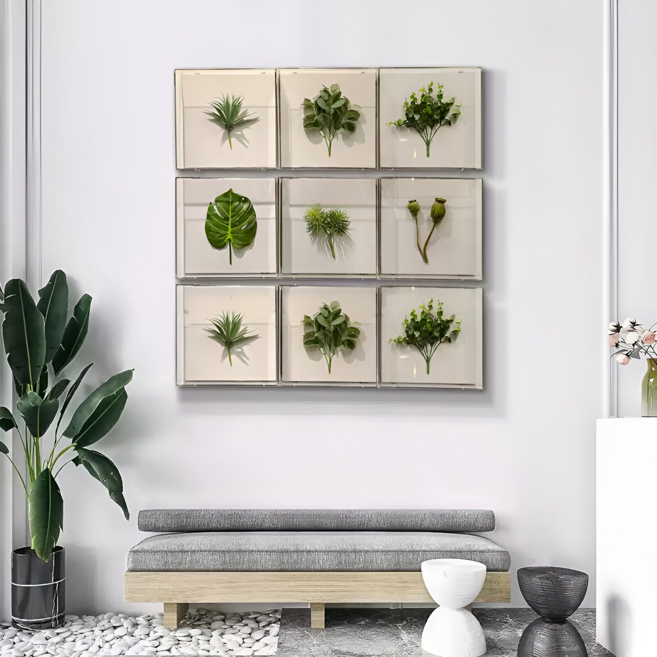 A modern Nordic interior features a gray bench, white accent tables, potted plants, and Giant Sculptures' Florvara Botanical Leaves 9-Panel Acrylic 3D Wall Art displayed in a grid on a white wall.