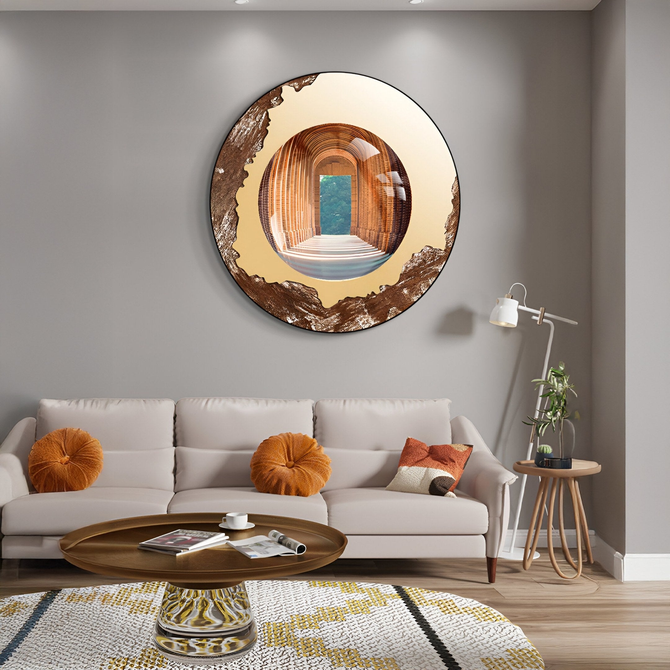 A modern living room with a beige sofa, round pillows, and wooden coffee table showcases the Portara Bronze Passage Illusion Round 3D Wall Art by Giant Sculptures, reflecting an arched hallway and green outdoor views for an architectural effect.