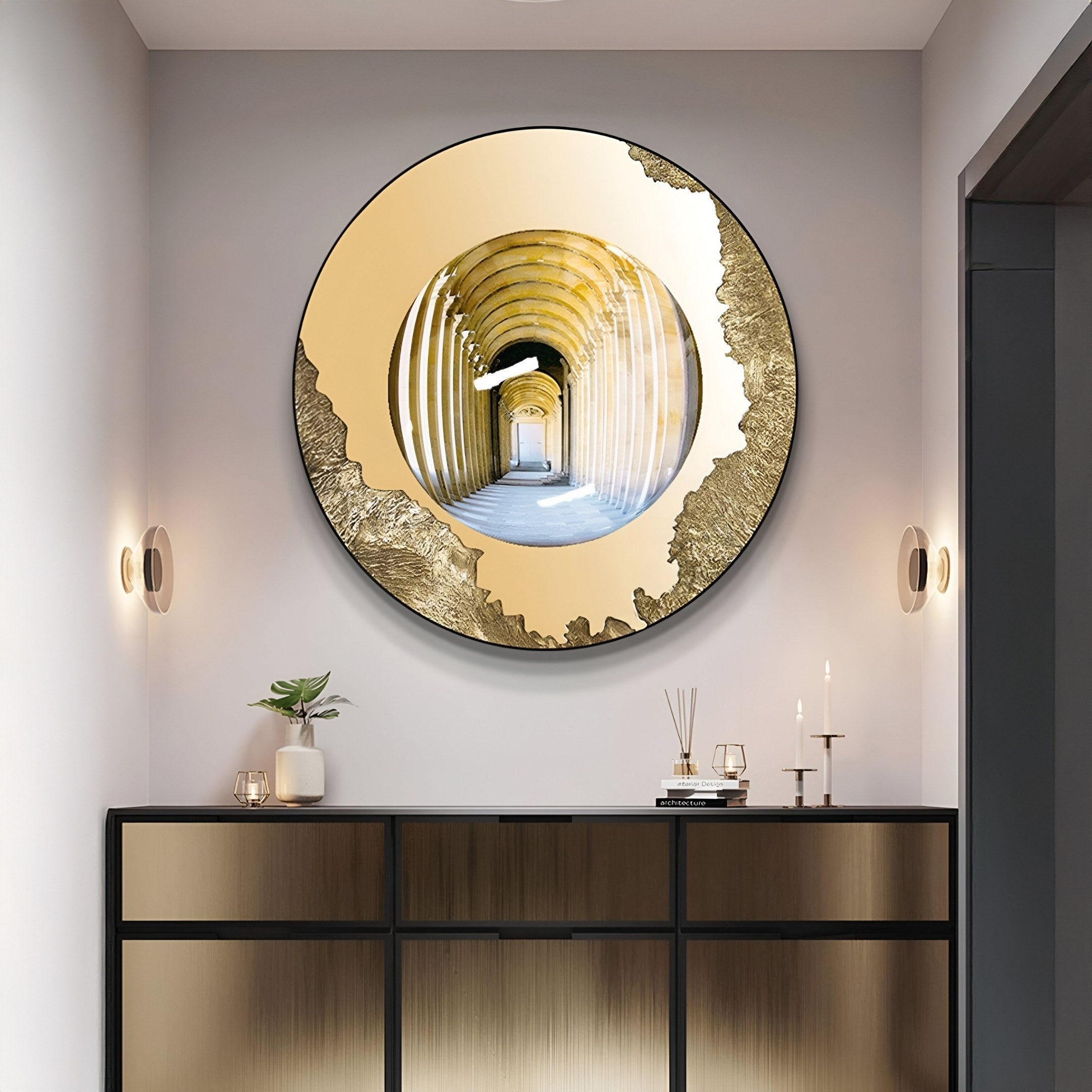 A modern hallway features the Portara Golden Archway Illusion Round 3D Wall Art by Giant Sculptures reflecting an arched corridor, with minimal decor—a plant, candles, glasses on a sleek sideboard—and wall-mounted lights flanking the piece.