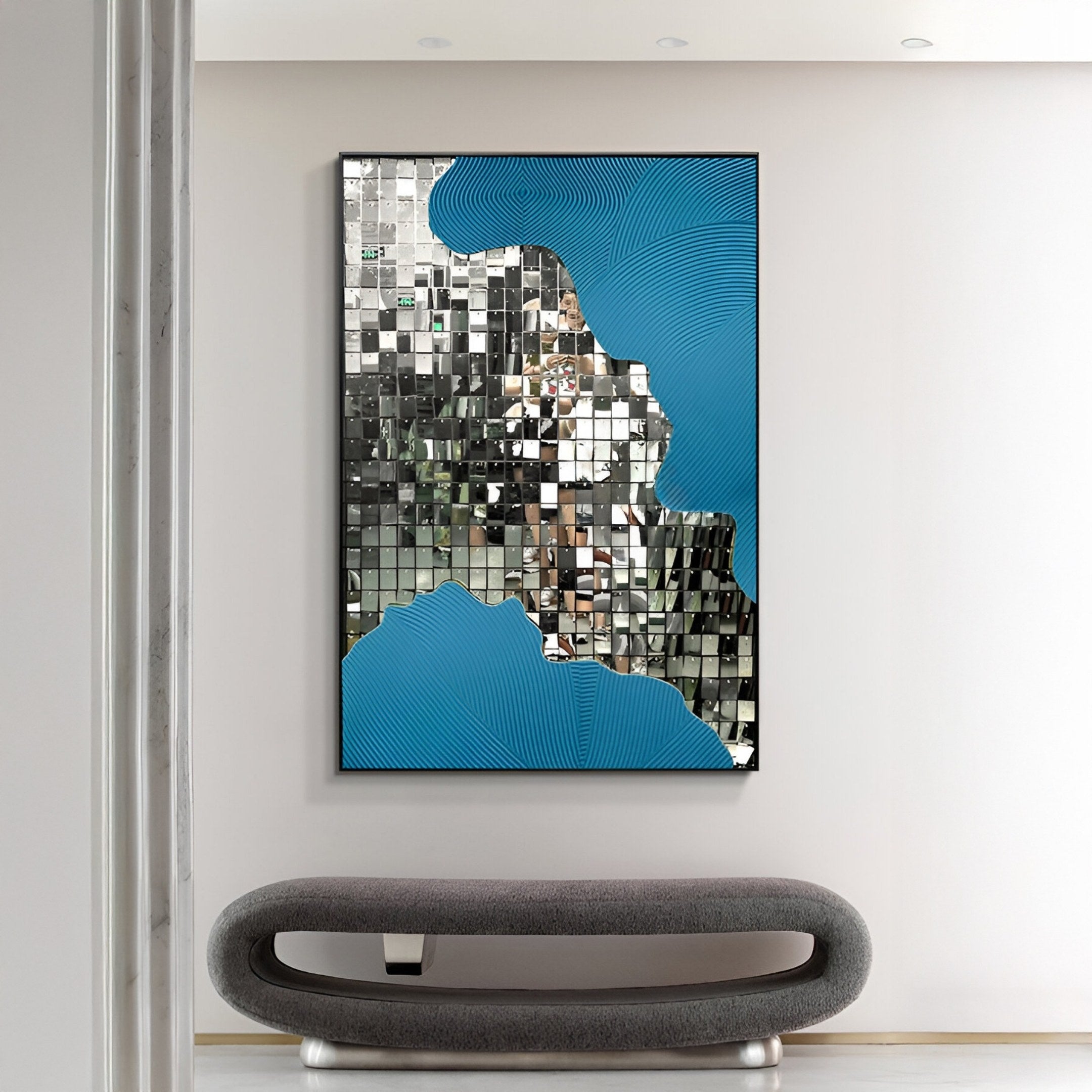 A modern interior showcases the Miravine Blue Hand-Painted Acrylic Mirror 3D Wall Art by Giant Sculptures above a gray oval bench, with mirrored and blue patterns reflecting the room and part of a standing person.
