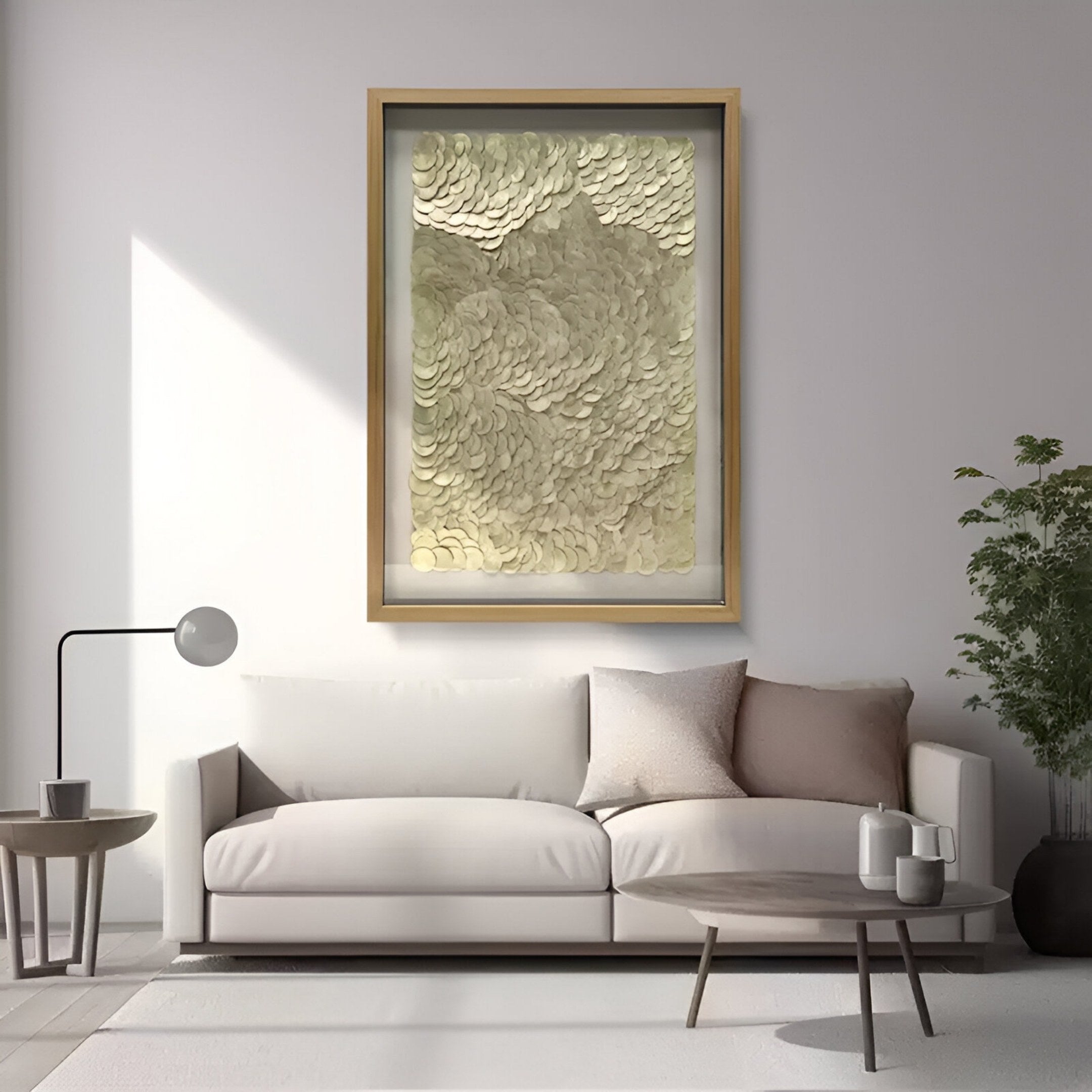 A modern living room with a beige sofa, neutral pillows, a round coffee table, a floor lamp, a potted plant, and the Giant Sculptures Orraya Golden Shell Disc Layered Framed 3D Wall Art displayed on the wall.