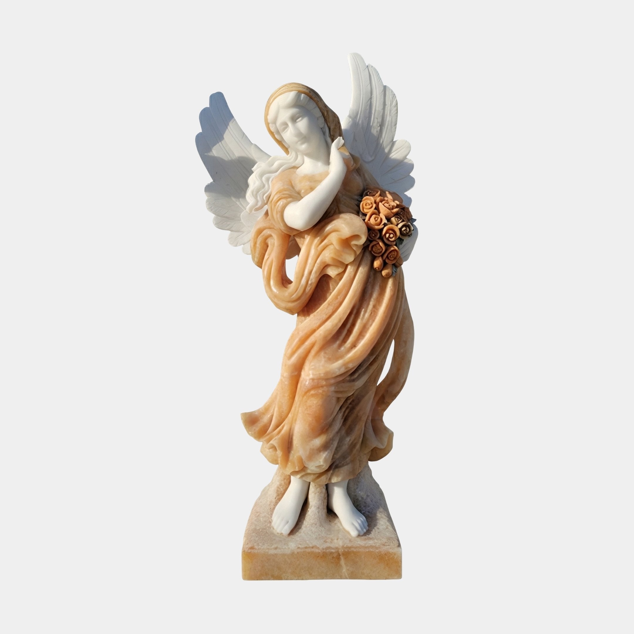 Beige Onyx Angel Marble Outdoor Sculpture by Giant Sculptures, depicting a winged female angel in flowing honey-toned robes holding roses, on a square stone base against a plain light background.