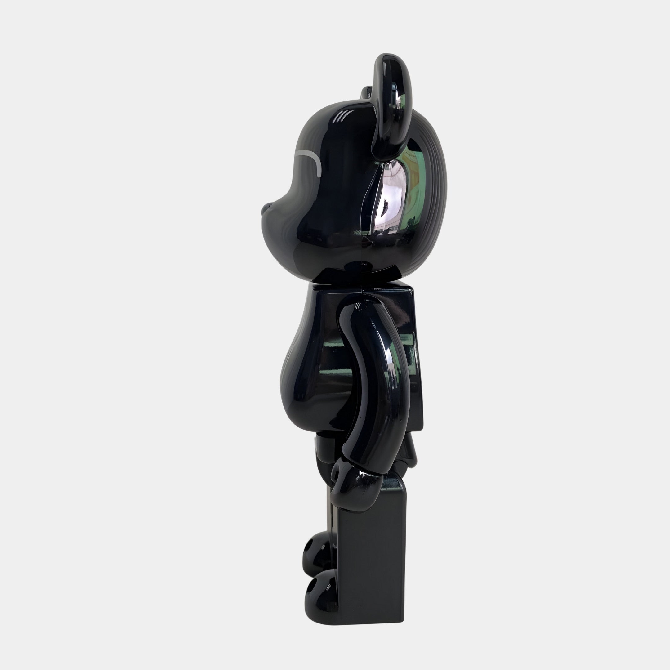 The Midnight Crest Bear Sculpture - 70cm by Giant Sculptures stands upright in profile, featuring rounded ears and a shiny piano-gloss black resin finish that gleams against a plain light gray background.
