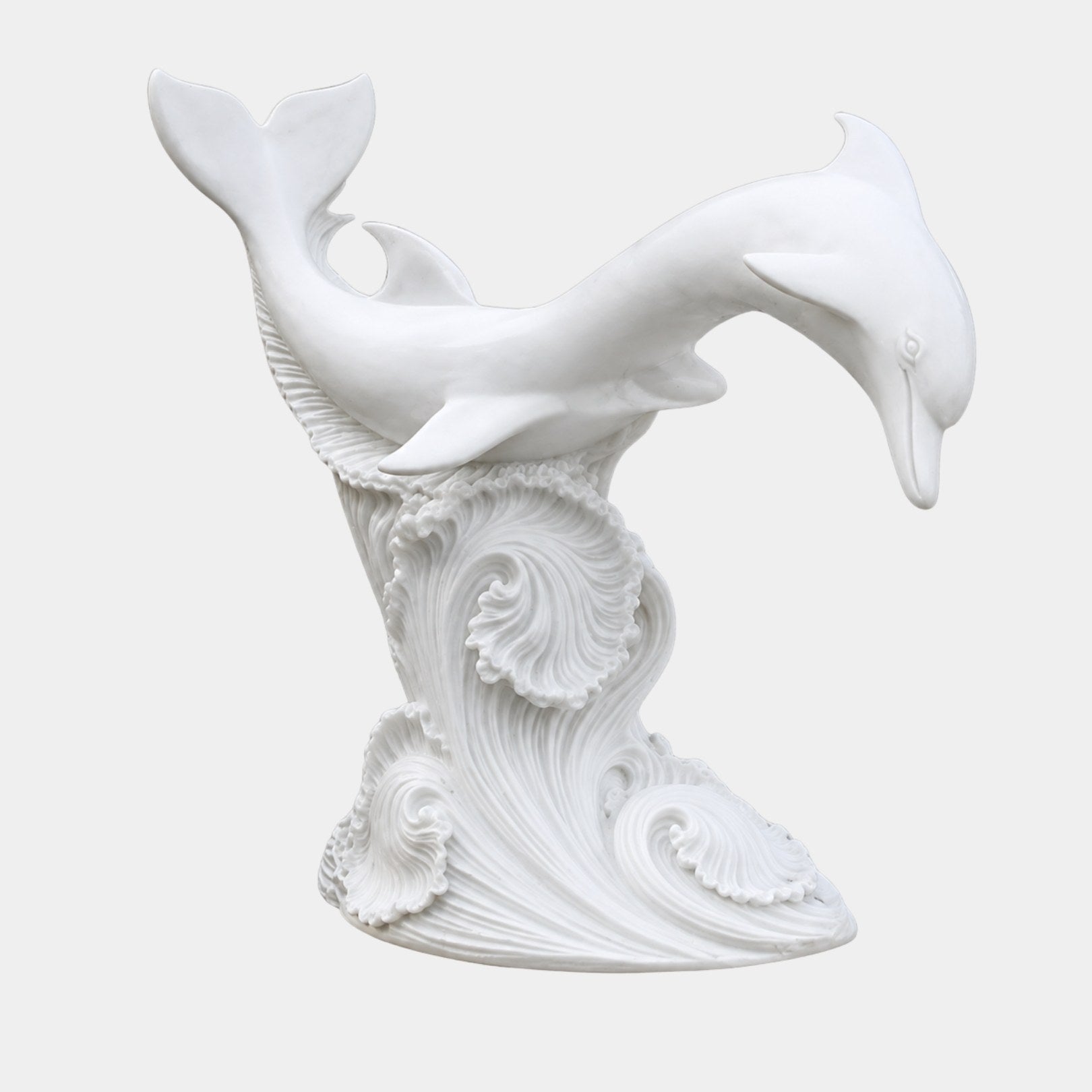 Two white marble dolphins diving over a tall column of carved breaking water