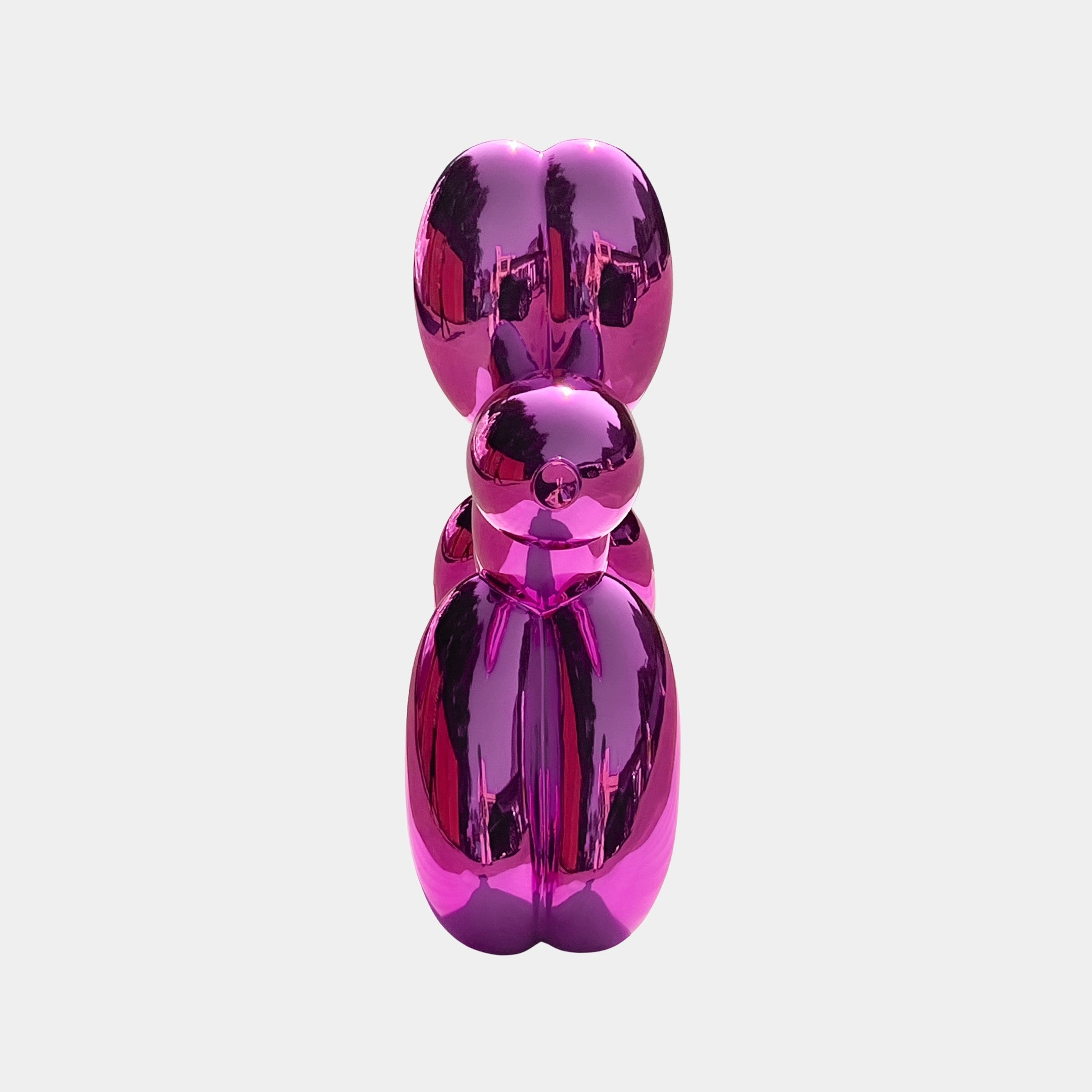 The Flamingo Pink Balloon Dog Sculpture - 80cm by Giant Sculptures features a shiny, reflective metallic surface that displays striking distorted reflections, making it a bold centerpiece for modern spaces.