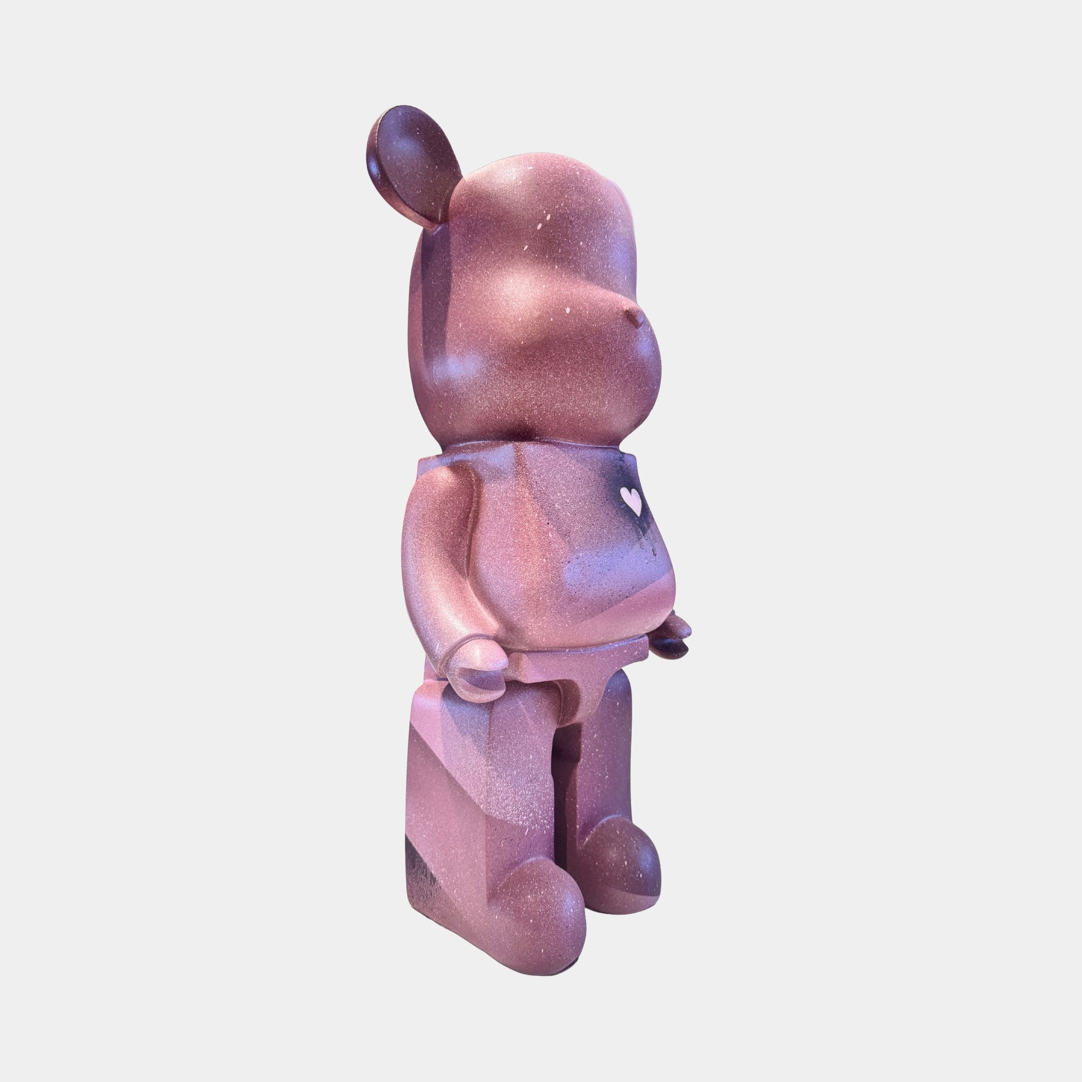 The Pinque Bear Sculpture - 50cm by Giant Sculptures features a pink and purple design, rounded shape, shiny speckled finish, and a small white heart on its chest—an eye-catching limited edition art piece.