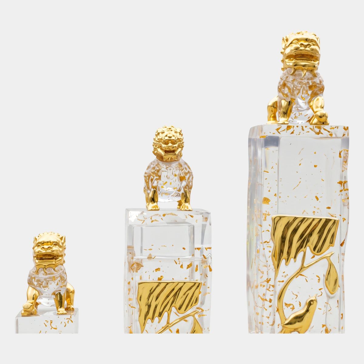 Clear Gilded Tree Column Cast Resin Sculpture in three heights (135/158/200cm), each topped with a gold-headed guardian lion and gold tree relief, on a plain white background.