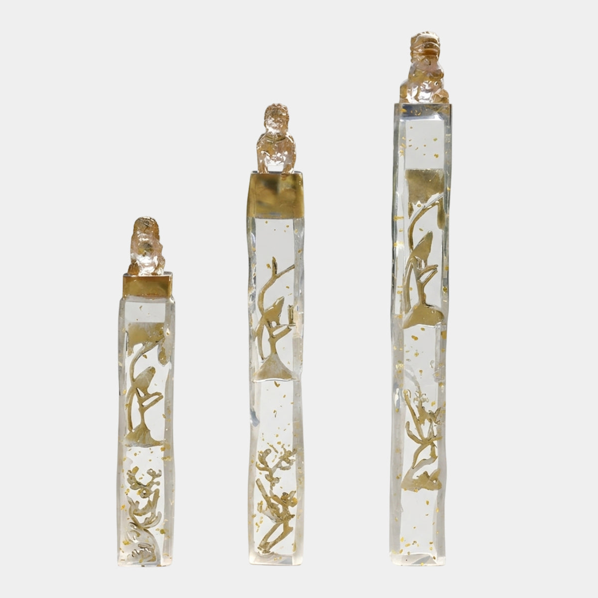 Clear Gilded Relief Column Resin Sculptures in three heights (100/130/150cm) by Giant Sculptures, with gold leaf accents, bird and blossom motifs, and clear resin guardian lions on top, shown on a plain white background.