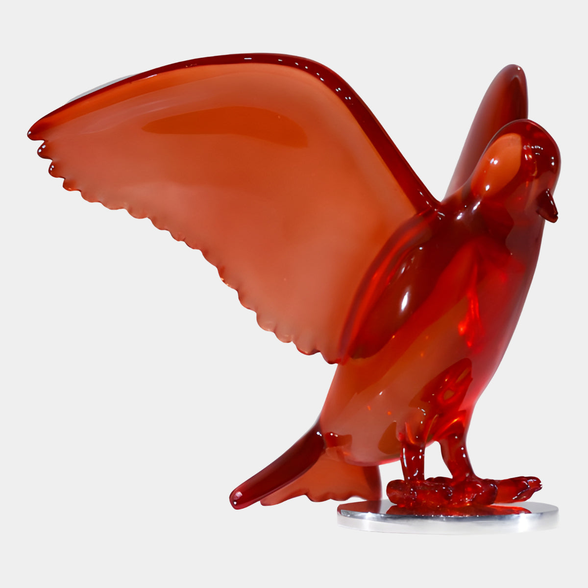 Red Raised-Wing Bird on a Metal Disc - 28cm, translucent red resin sculpture with wings swept up, standing on a polished metal disc against a plain white background.