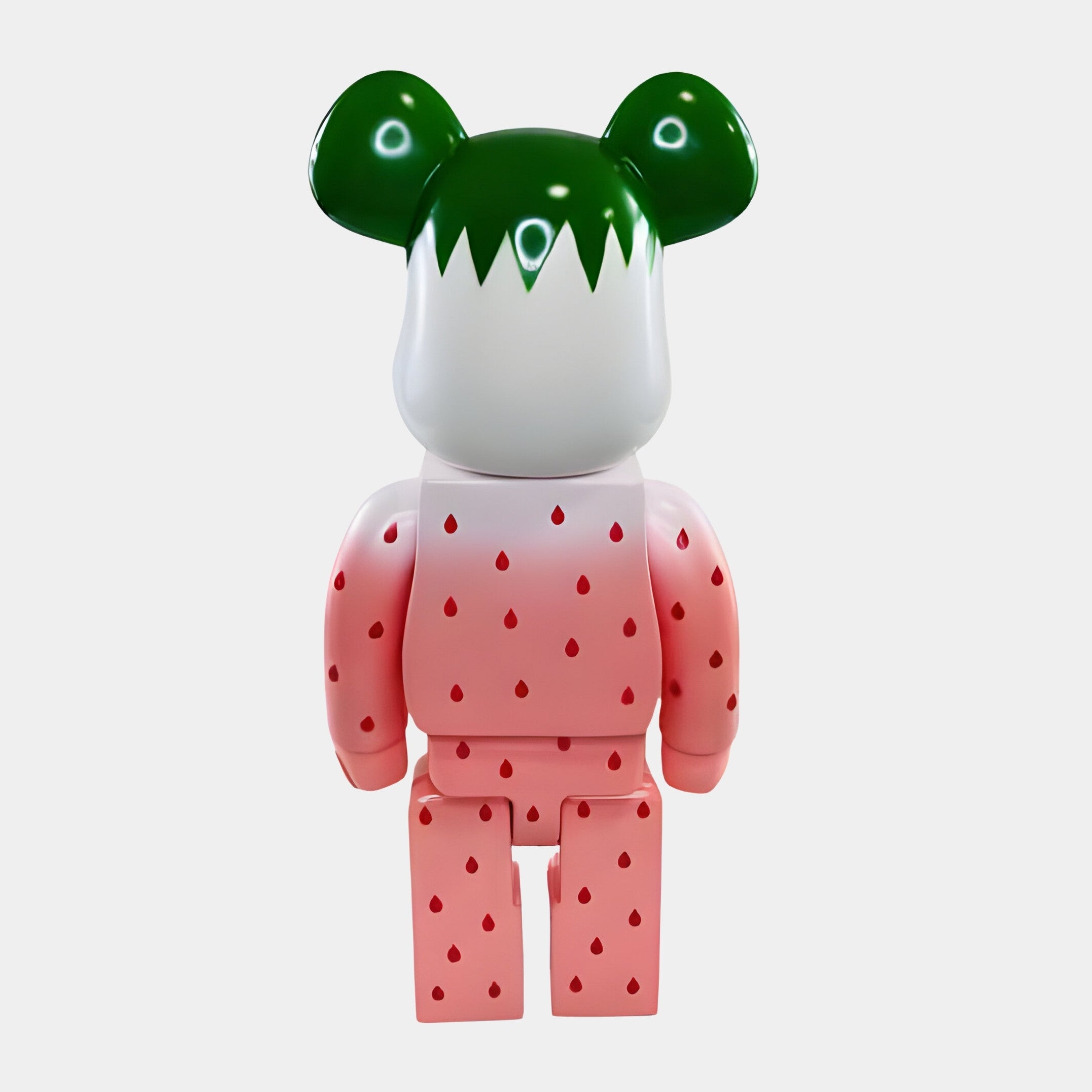 The Seeded Gradient Bear Sculpture - 70cm by Giant Sculptures features a pink body with red strawberry seed patterns, green ears, and a white top like a strawberry crown, shown from the back on a plain white background.