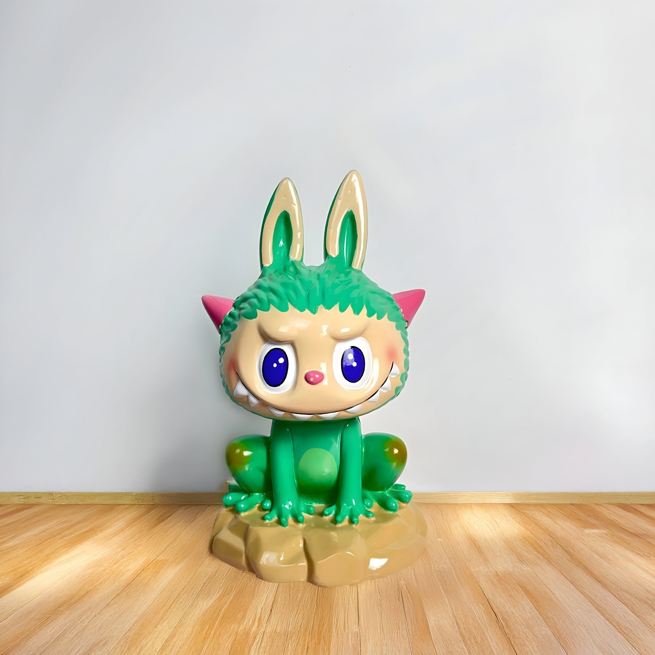 The Monster Frog Labubu Sculpture - 100cm by Giant Sculptures features a playful frog alien with bunny ears, green fur, big blue eyes, sharp teeth, and pink cat-like ears—ideal for adding character to premium interiors.