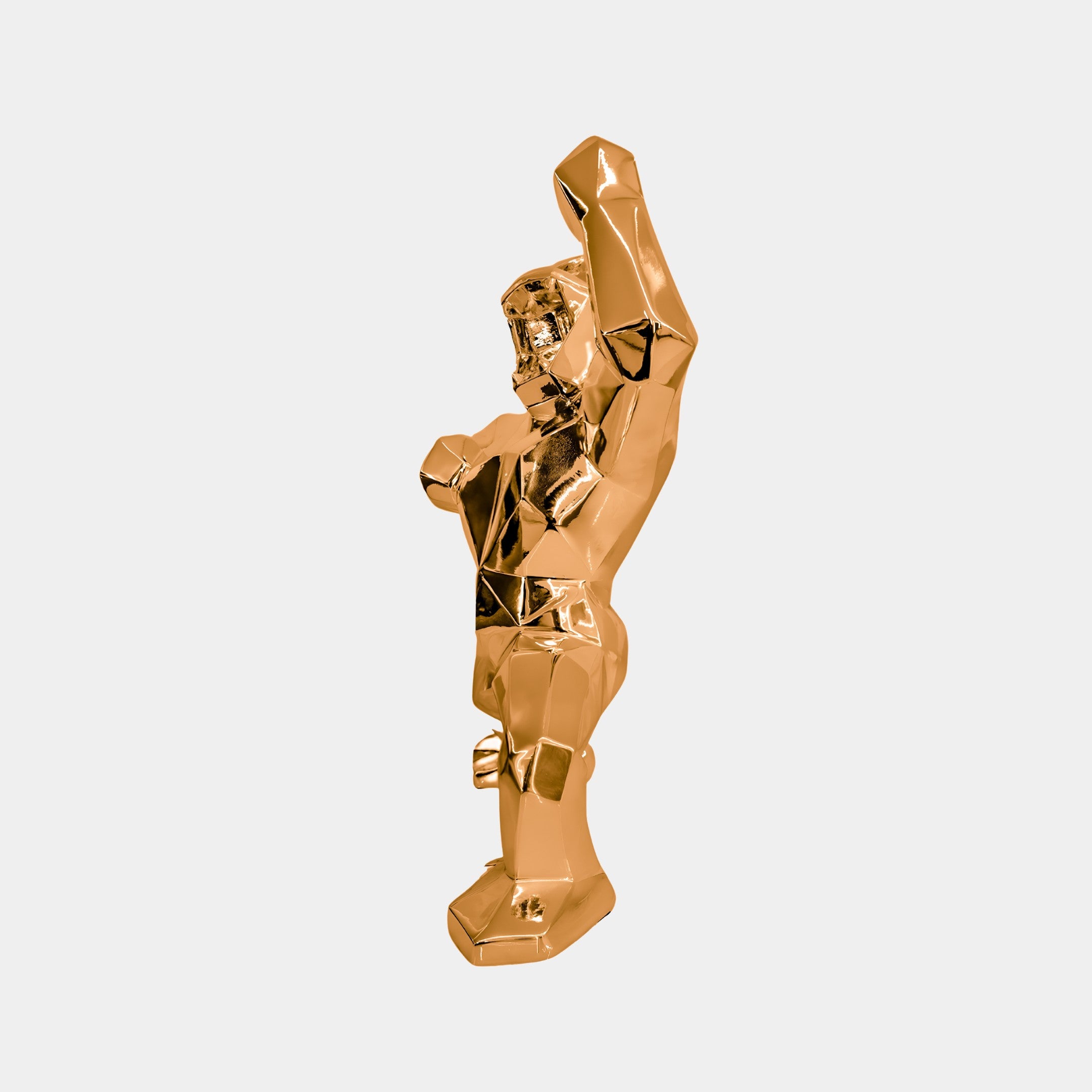 The Rose Gold Gorilla Sculpture by Giant Sculptures, standing 50cm tall, captivates as a modern centerpiece with its polygonal design. On its hind legs with a raised arm, this angular creature showcases exquisite geometric facets in an artful display of strength and elegance.