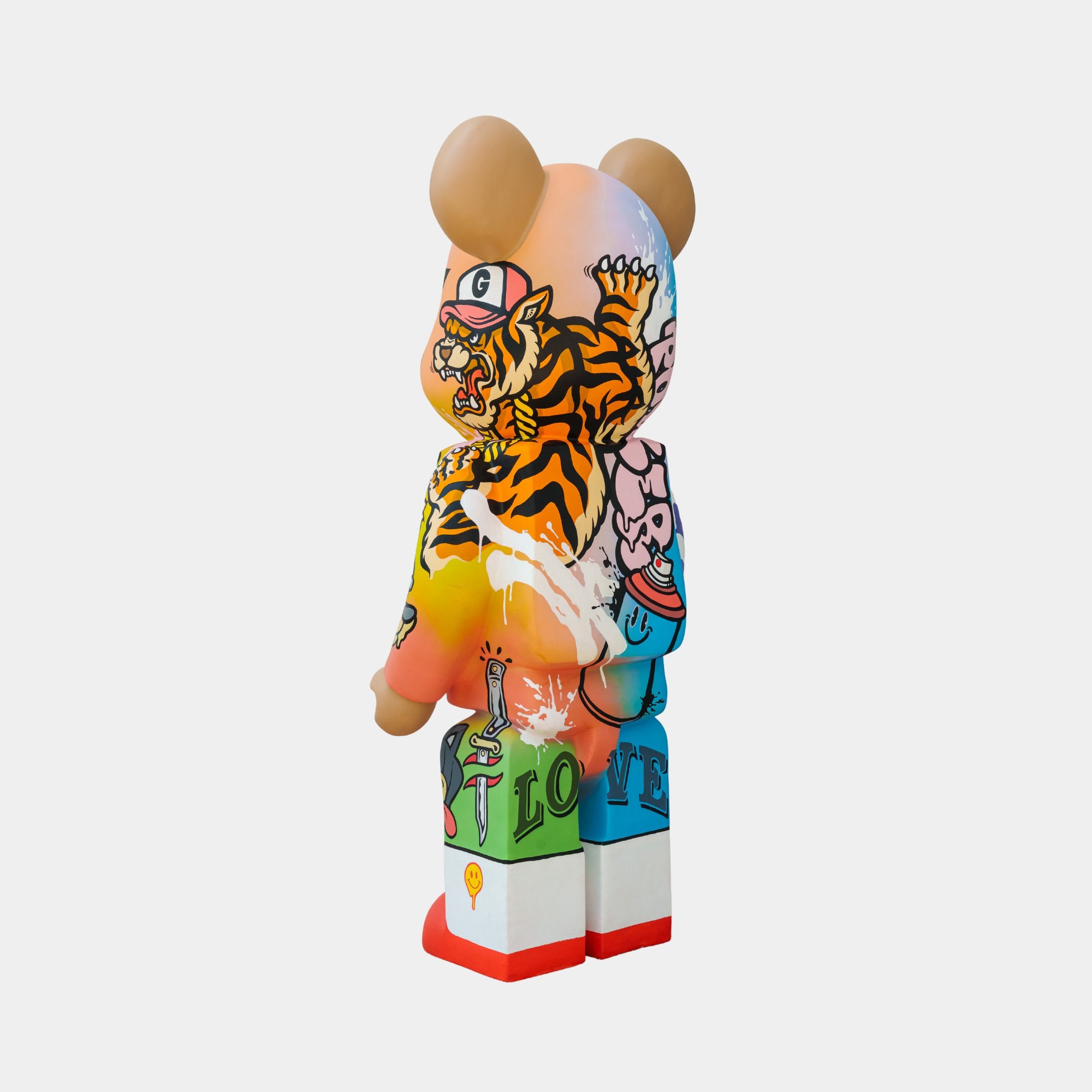 Introducing the Giant Sculptures Lucky Paws Bear Sculpture - 50cm, a vivid piece in the BigDel collection. This limited edition bear features cartoon designs, a playful tiger on its back, colorful bursts with LOVE on its legs, and stands proudly on red shoes against a plain background.