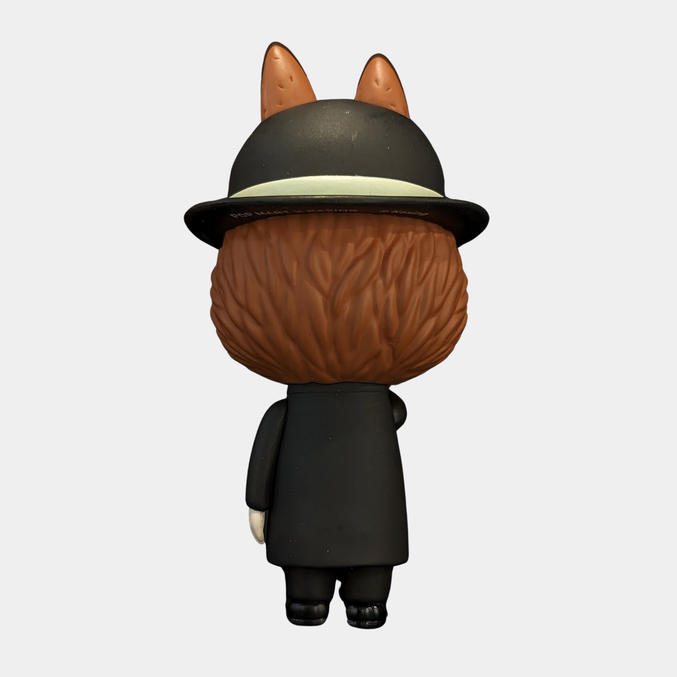 The Art History Apple Mystery Labubu Sculpture by Giant Sculptures (100cm) depicts an animal character with brown fur, upright ears, a black hat with a pale band, a long black coat, and one hand tucked behind its back.