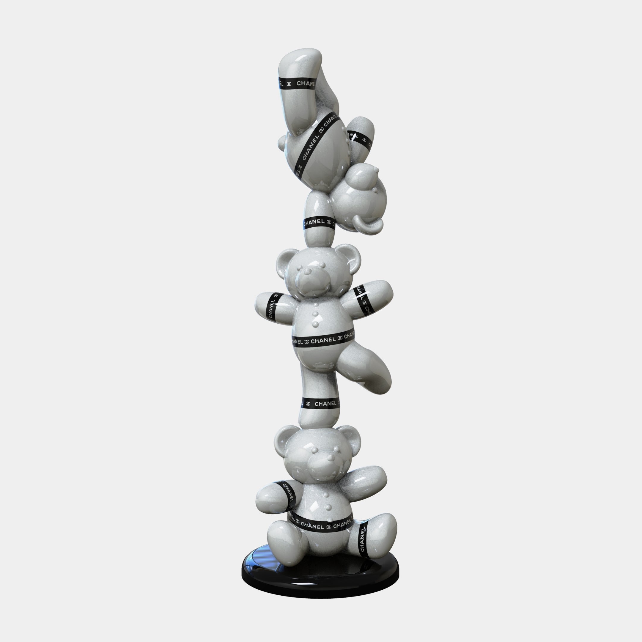 The Giant Sculptures Gacko Chanel Triple Bear Sculpture - 90cm features three white bears with black CHANEL ribbons stacked on a round black base, the top bear upside down, creating a striking display against a light gray background.