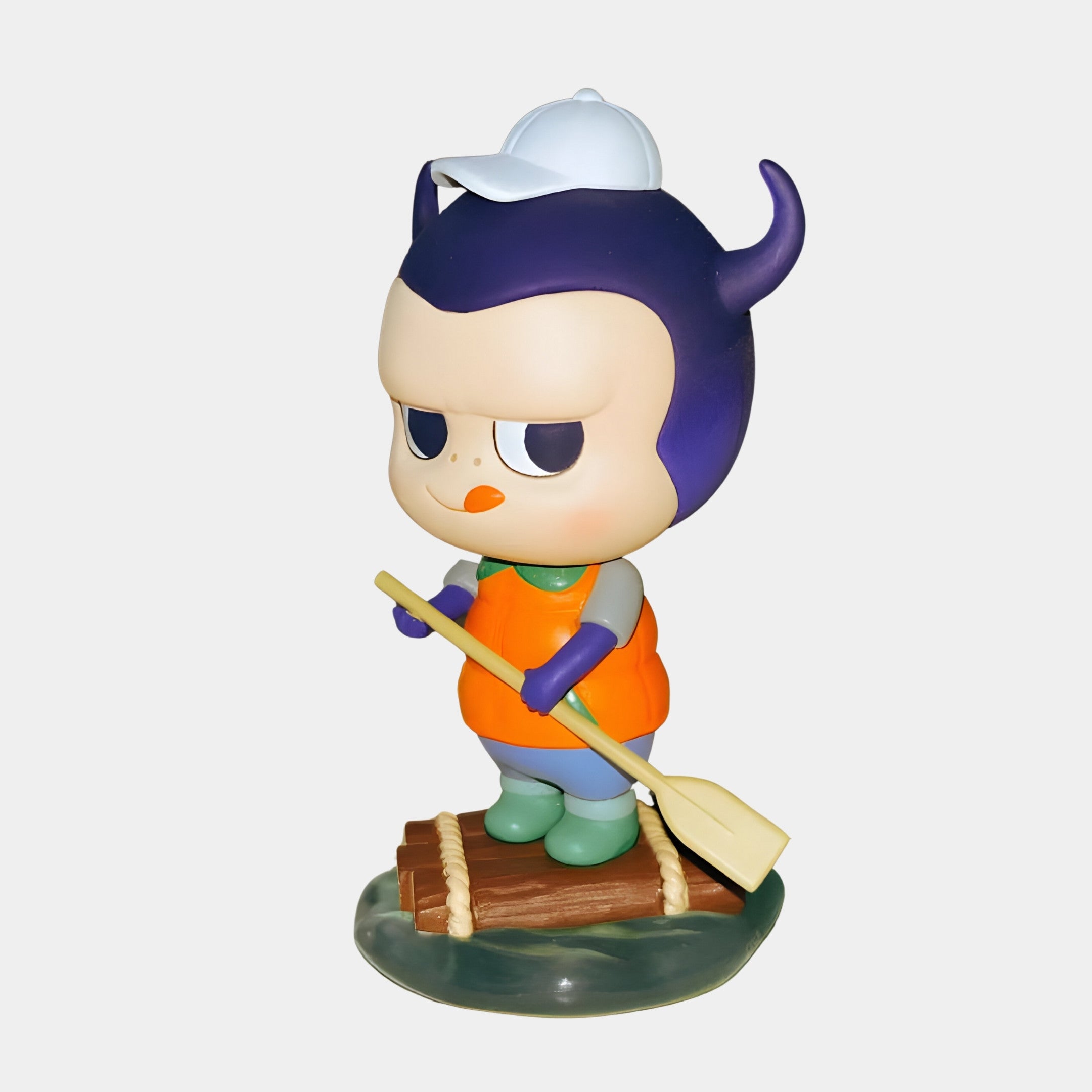 The Camp Life Rafter Labubu Sculpture - 160cm by Giant Sculptures features a whimsical character with purple horns, white cap, orange vest, green boots, and freckles paddling a small raft—perfect for playful décor.