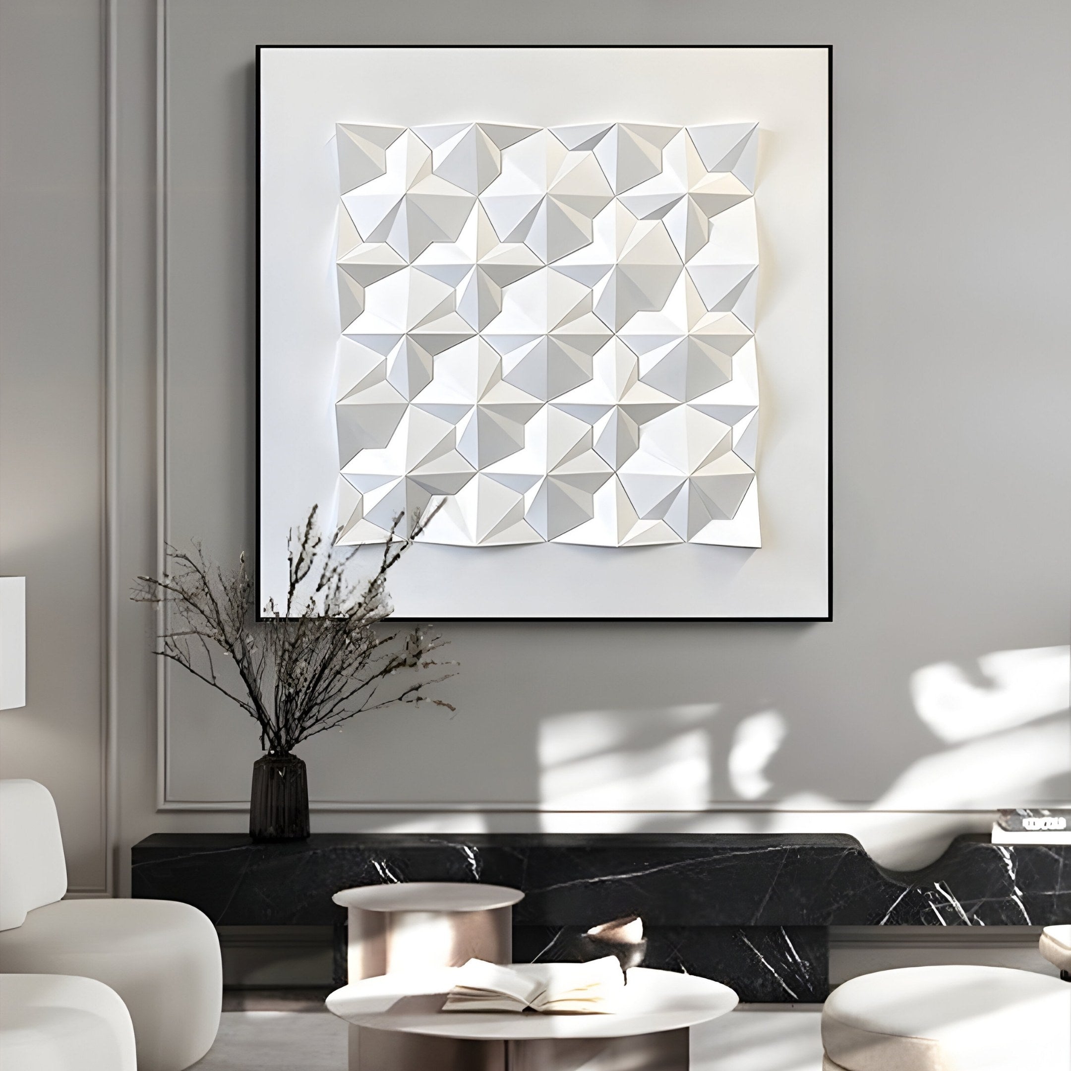 In a modern living room, the Geometrica Tessellated Cube White 3D Wood Relief Wall Art by Giant Sculptures adorns a gray wall, showcasing its geometric charm in a square frame. A black vase with dried twigs sits atop a sleek black marble console table, complemented by round tables and chairs nearby.