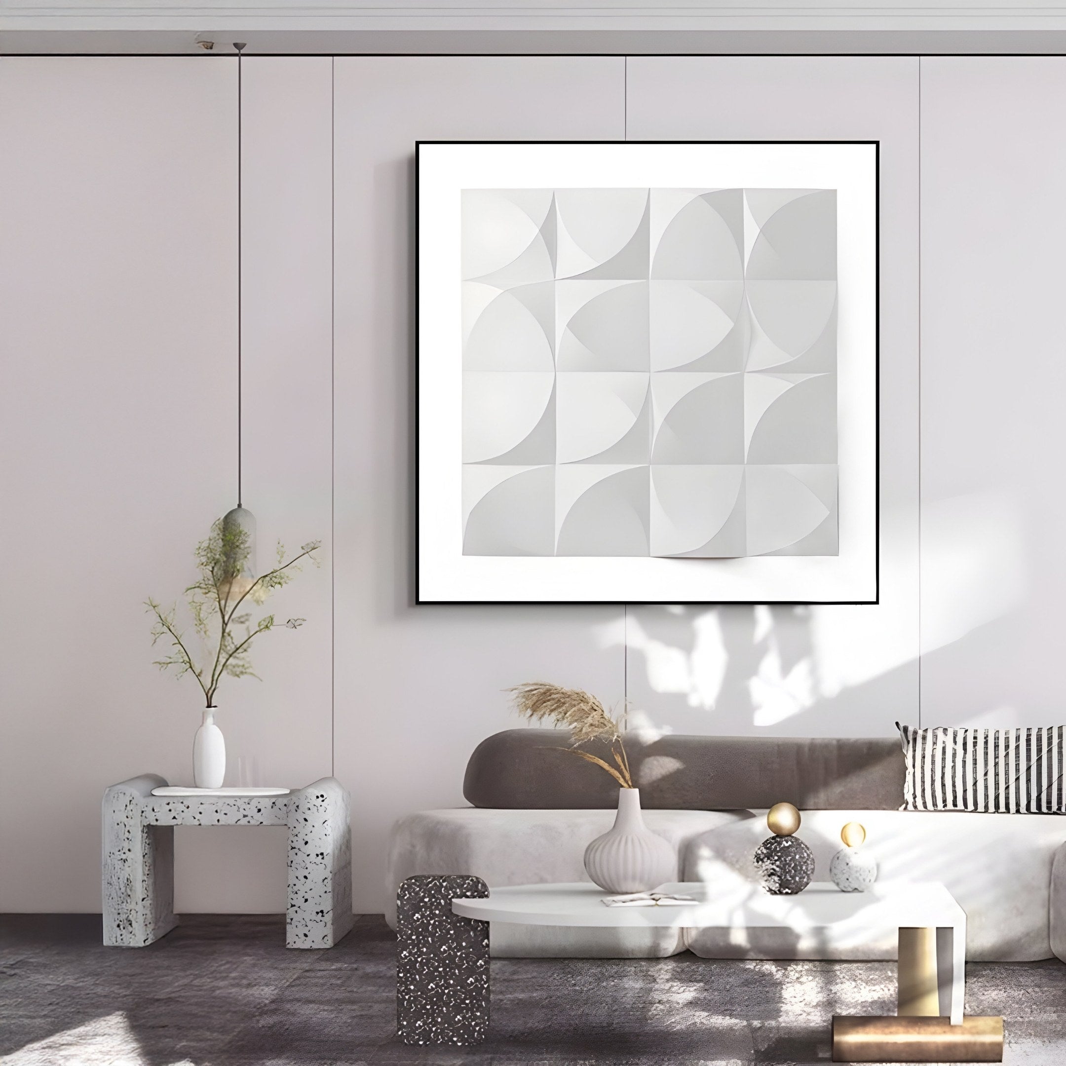 In a modern minimalist living room, the Geometrica Curved Patterned White 3D Wood Relief Wall Art by Giant Sculptures adorns the wall. A light gray couch with a striped pillow sits beside a small white table and a speckled side table featuring vases of tall, delicate plants.