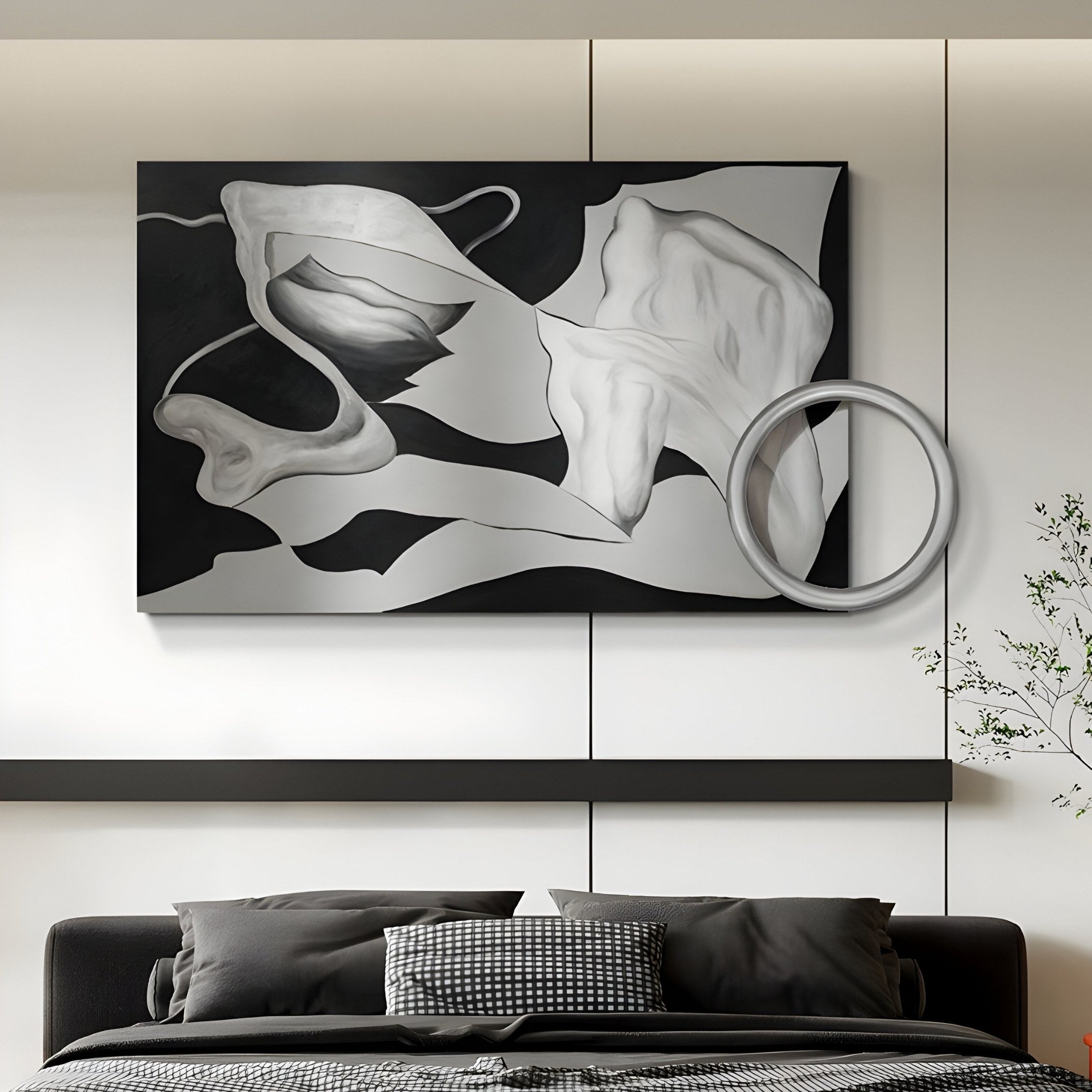 The Calmant Black & Silver Abstract Hand-Painted Wall Art by Giant Sculptures, featuring flowing shapes and a circular element, hangs above a modern bed with gray pillows and a dark blanket. A small plant to the right adds greenery, enhancing the minimalist wabi-sabi-inspired setting.