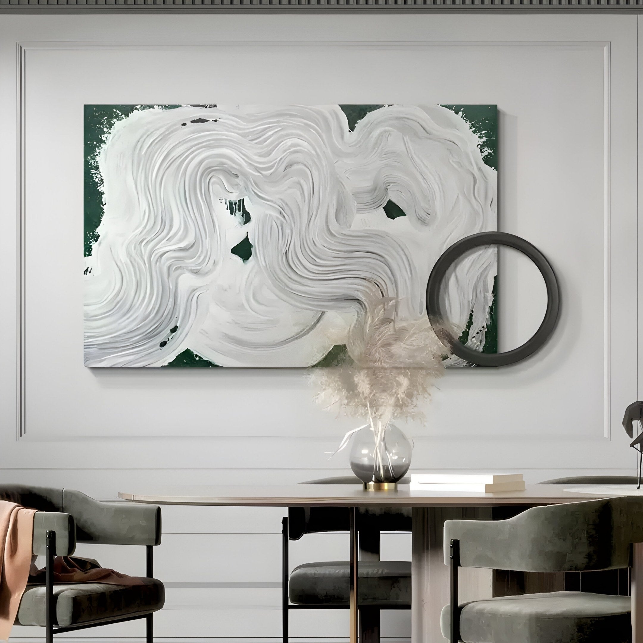A modern interior features the Giant Sculptures Calmant Green & White Abstract Hand-Painted Wall Art with swirling patterns on a dark green background. Beneath it, a minimalist desk holds a glass vase with dried plants and a round black decor piece leaning against the wall.