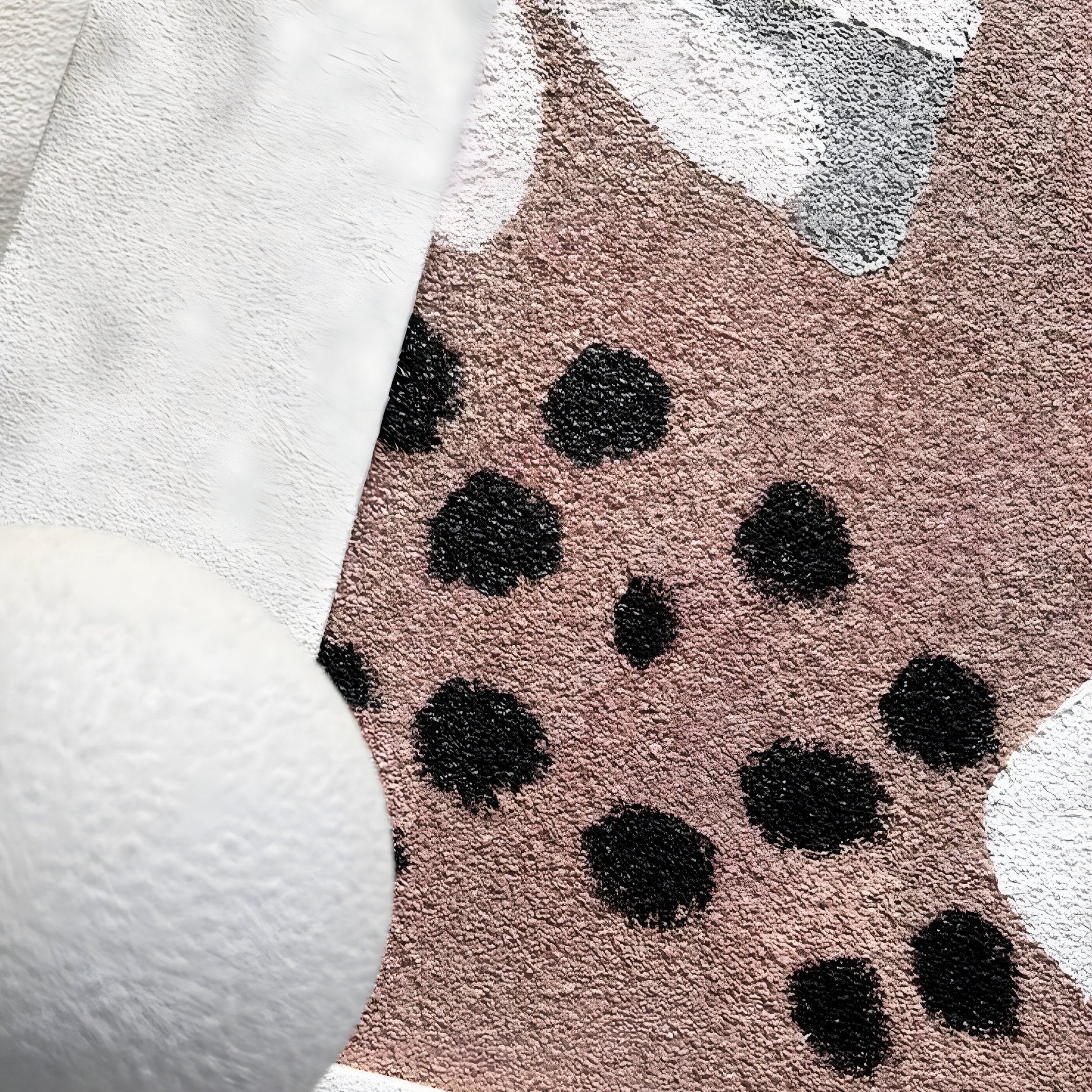 The Florere Neutral Bloom Hand-Painted Sandstone 3D Wall Art by Giant Sculptures showcases a textured surface with tan and gray hues, accented by black spots. Its white, rounded edge adds contrast, enhancing the speckled designs depth and dimension.