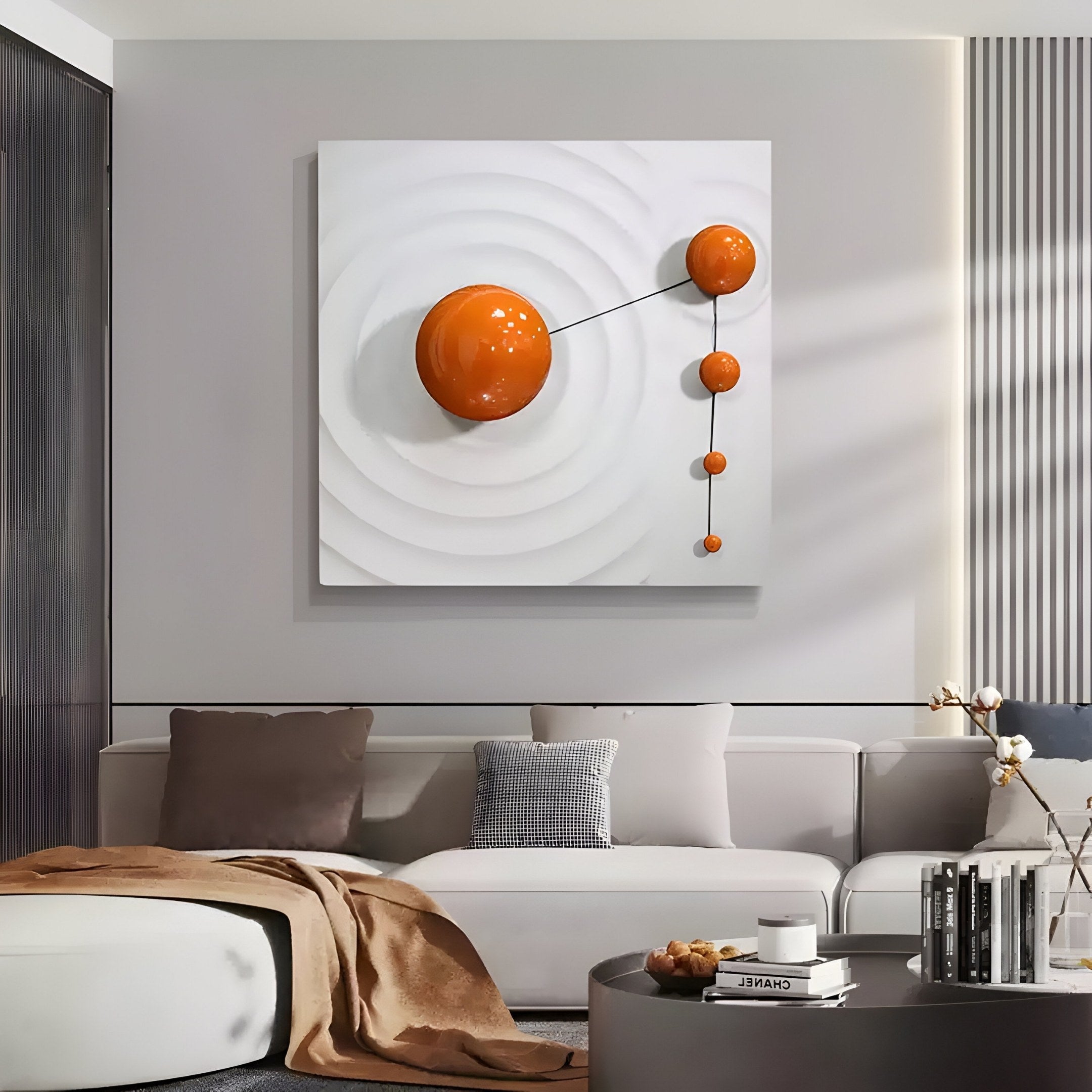 In a modern living room, Giant Sculptures Galactica White Wood Relief 3D Wall Art With Orange Metal Ball serves as the centerpiece. A white sectional sofa, cushions, brown throw, and glass coffee table complement the neutral decor in this harmonious setting.