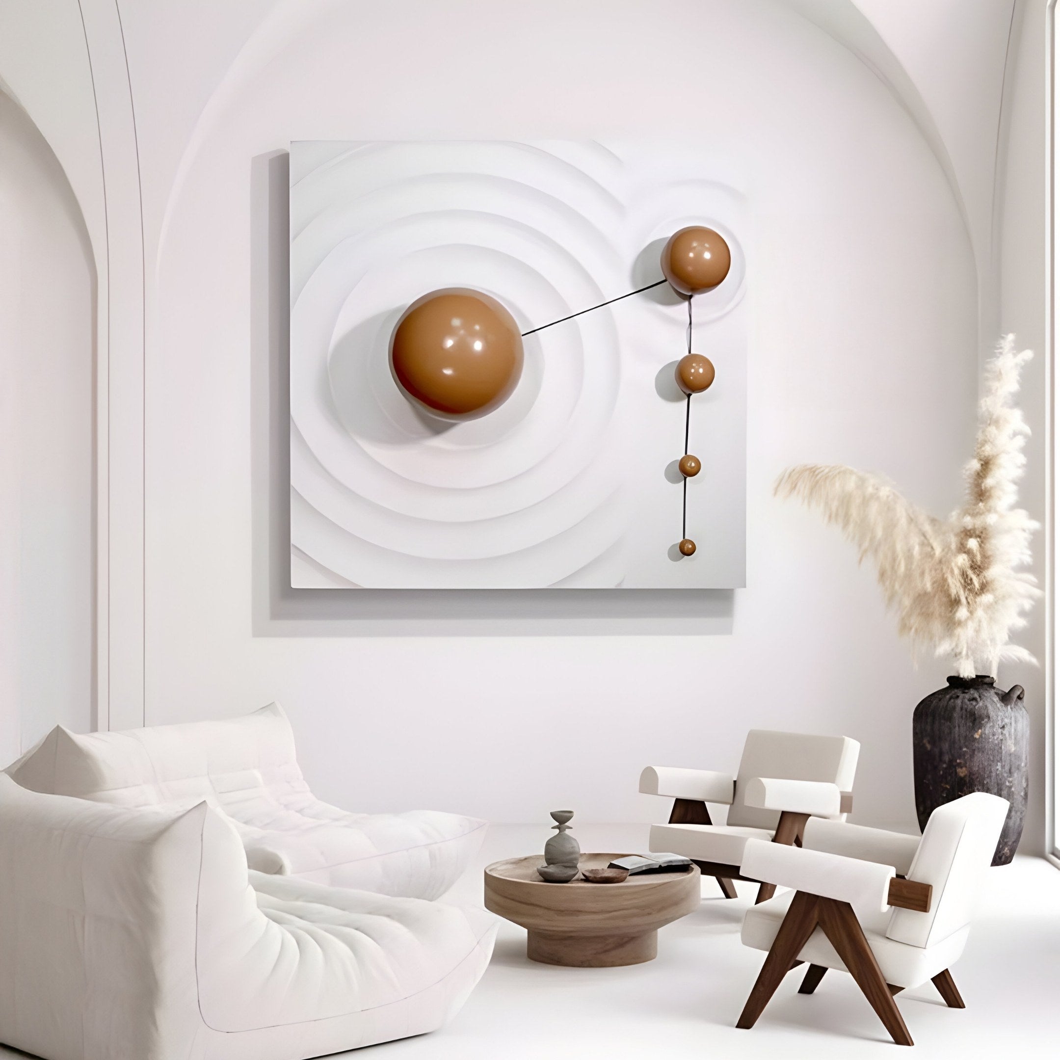 A minimalist living room features white furniture and the Galactica White Wood Relief 3D Wall Art with brown metal ball by Giant Sculptures. A vase with pampas grass complements a small round coffee table adorned with tasteful decor items.