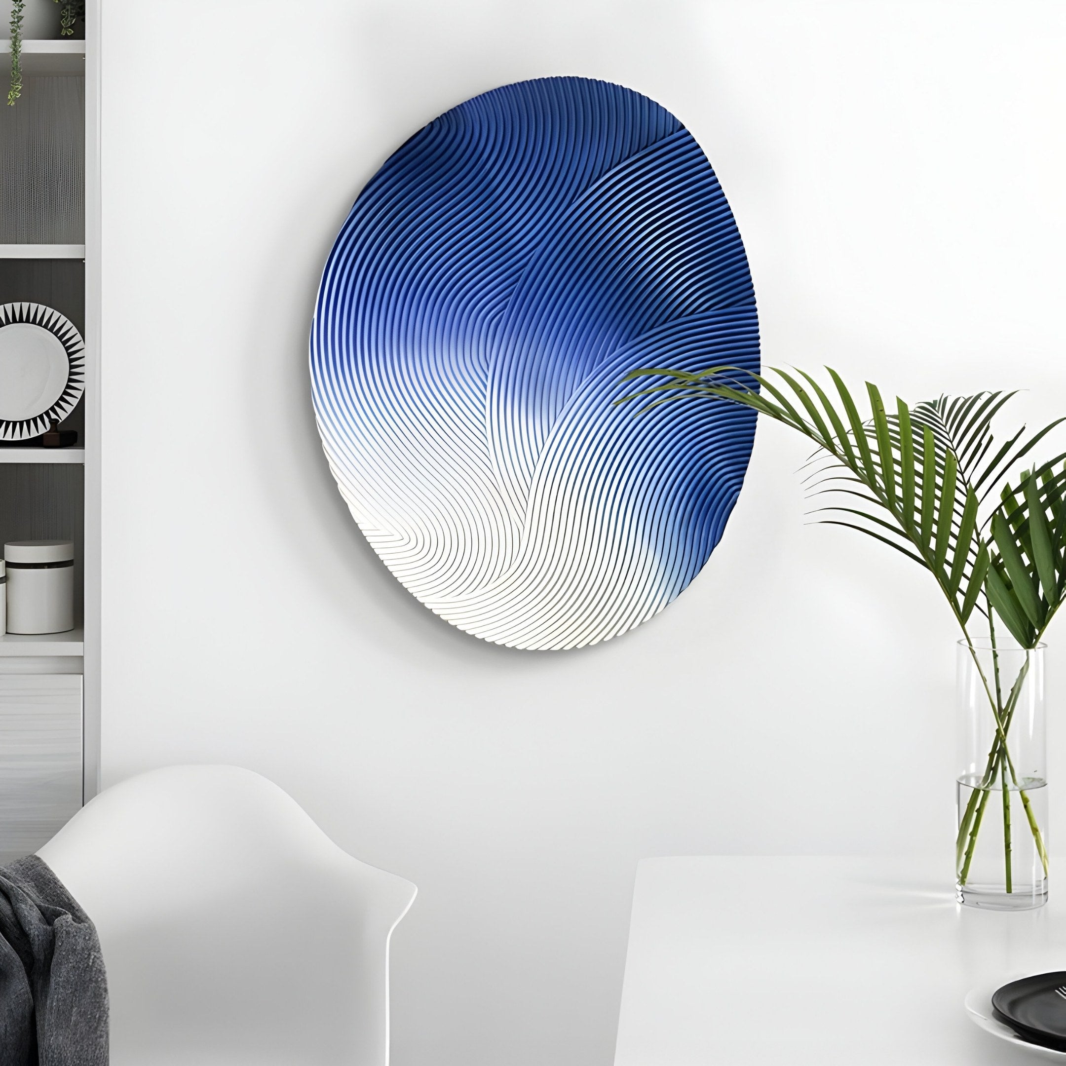 The Fluctus Blue Textured Sandstone Wood Relief 3D Wall Art by Giant Sculptures, with its swirling gradient from blue to white, enhances the modern minimalistic rooms vibe, perfectly complementing the sleek white chair and potted plant.