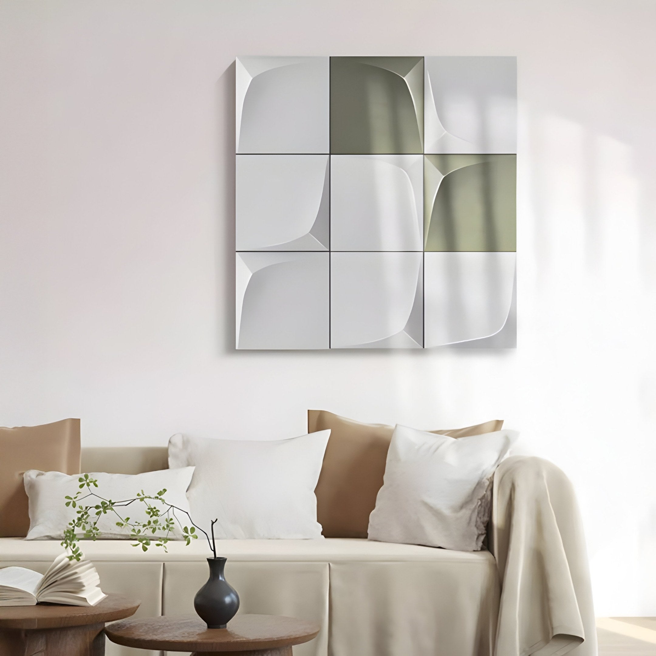 A contemporary living room showcases a white couch with beige pillows. The Curvatura White & Olive 3D Wood Relief Wall Art by Giant Sculptures adorns the wall. In the foreground, a small wooden table displays an open book and a vase of leaves, enhancing the modern aesthetic.