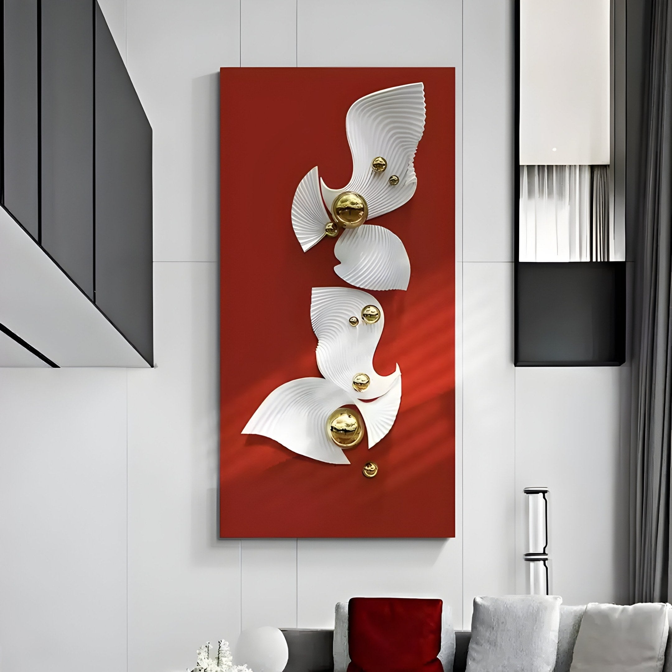The Aurelia Red & White 3D Wood Wall Art With Metal Ball by Giant Sculptures features embossed white, fan-like shapes and gold spheres on a vertical red panel. It complements a modern living room with a grey sofa, red and white cushions, and a tall silver floor lamp against the white wall.