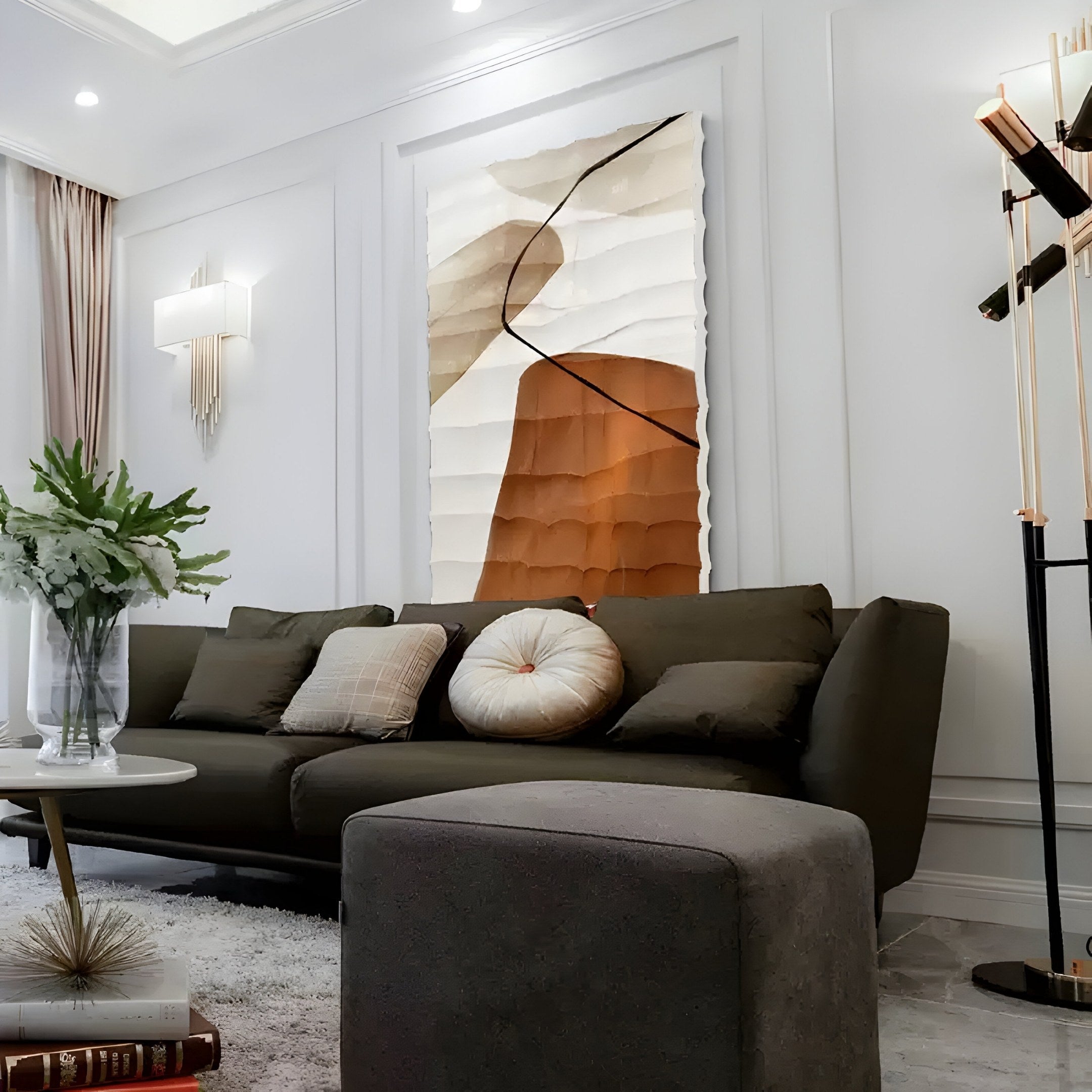 The modern living room showcases a dark green sofa with pillows, textured abstract art, and a plush ottoman. A vase of green plants adorns the round coffee table, while stylish sconces illuminate the exquisite Terracurve IV Hand-Painted Sandstone Wood Relief 3D Wall Art by Giant Sculptures.