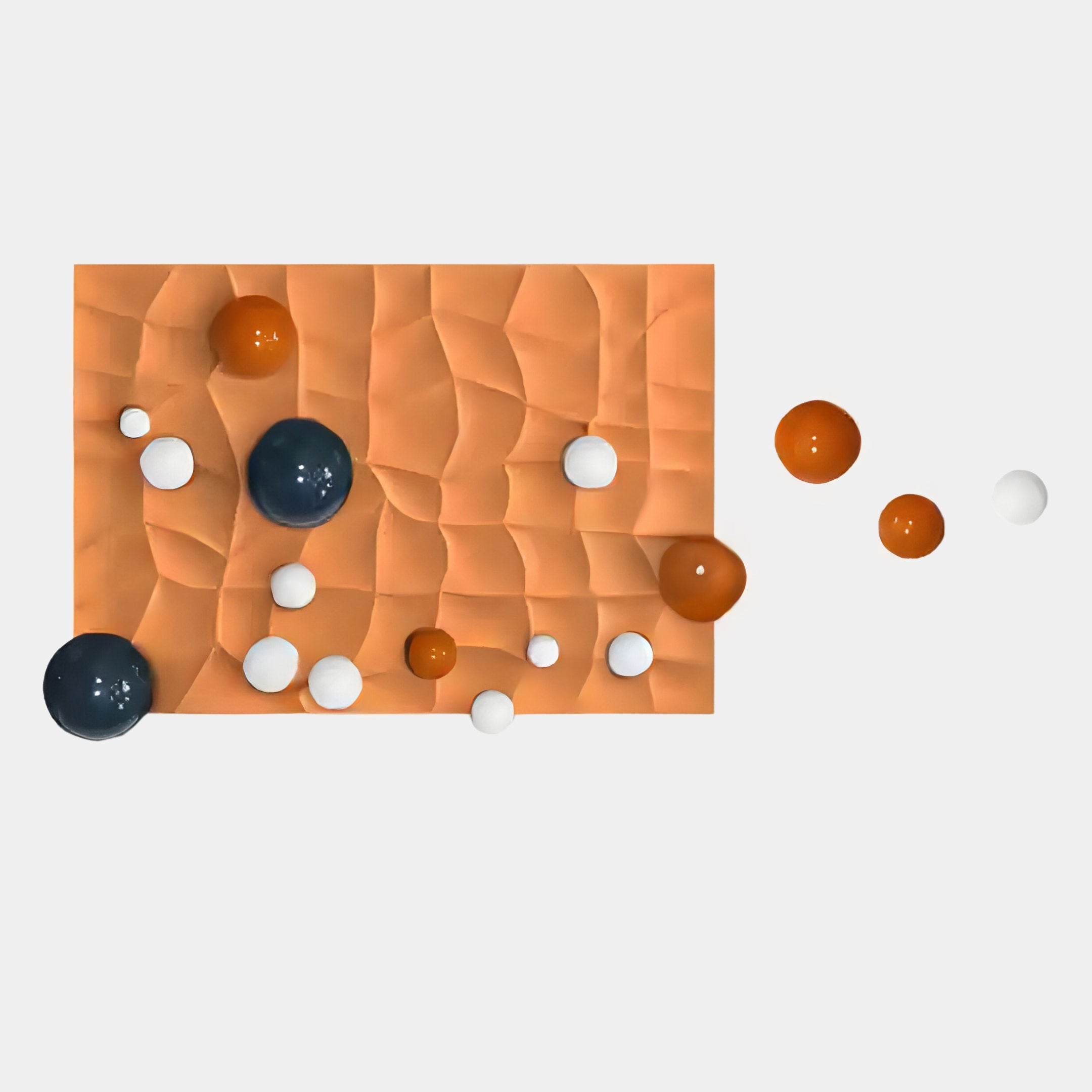 A striking abstract image of Giant Sculptures’ Orbison Terracotta 3D Wood Relief Wall Art With Floating Metal Ball, featuring a textured orange panel with glossy navy blue, white, and orange spheres on a plain white background.