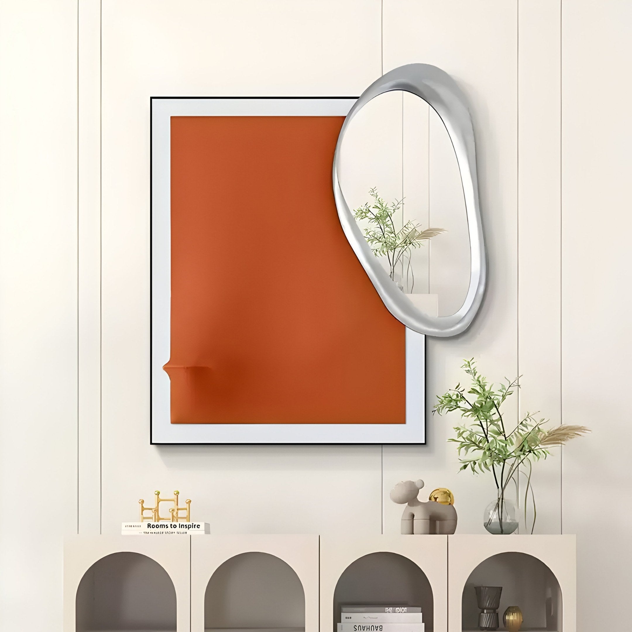 Wall art by Giant Sculptures showcasing the Reflectra Orange Wood Relief 3D piece with an adjacent silver mirror. Below, a shelf holds a toy, vase with green branches, and a gold decoration reading Room to Inspire, set against light wood paneling.