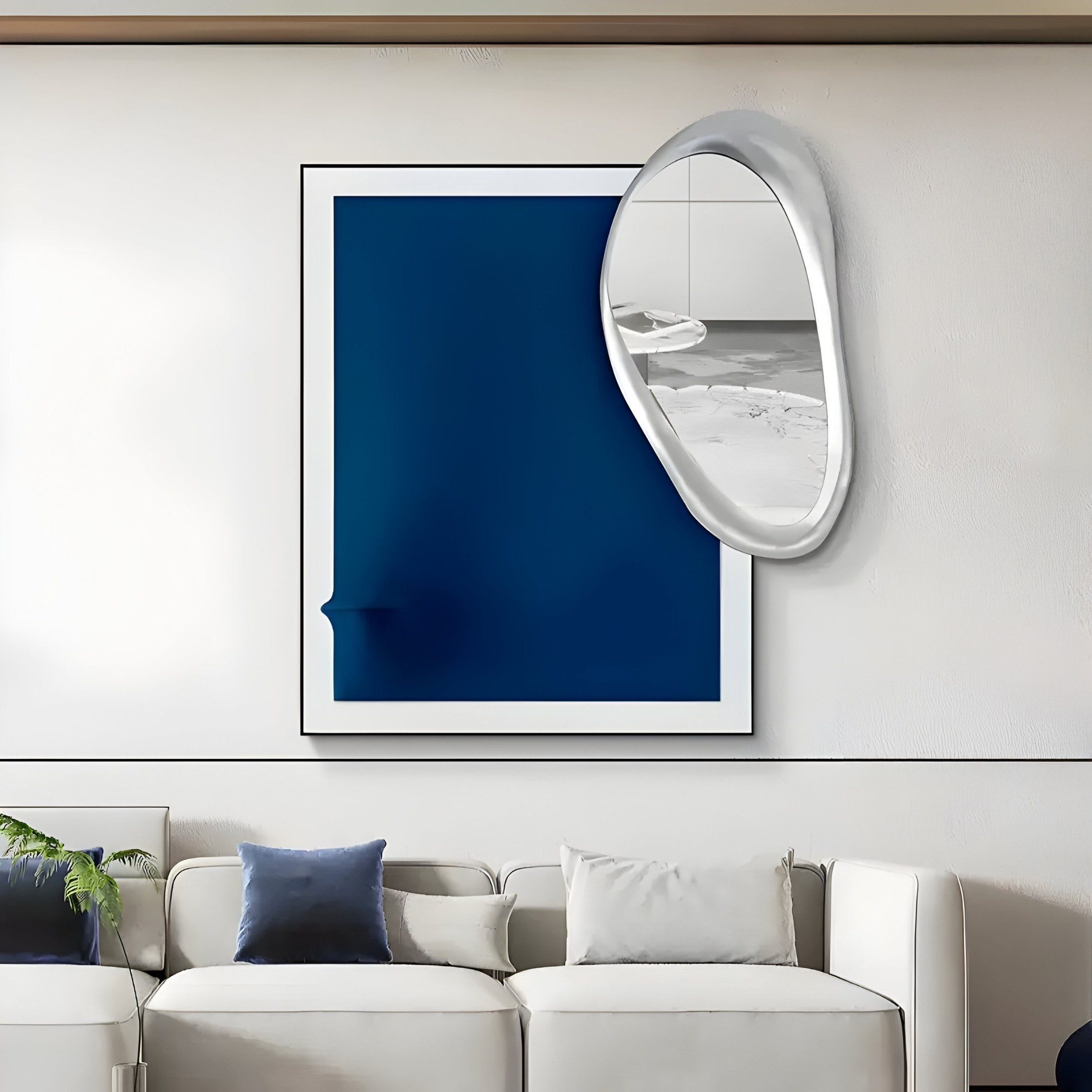 A modern living room features a white sofa with blue and white pillows. Above it hangs the Reflectra Deep Blue Wood Relief 3D Wall Art With Silver Mirror by Giant Sculptures, accompanied by a green plant partially visible on the left.